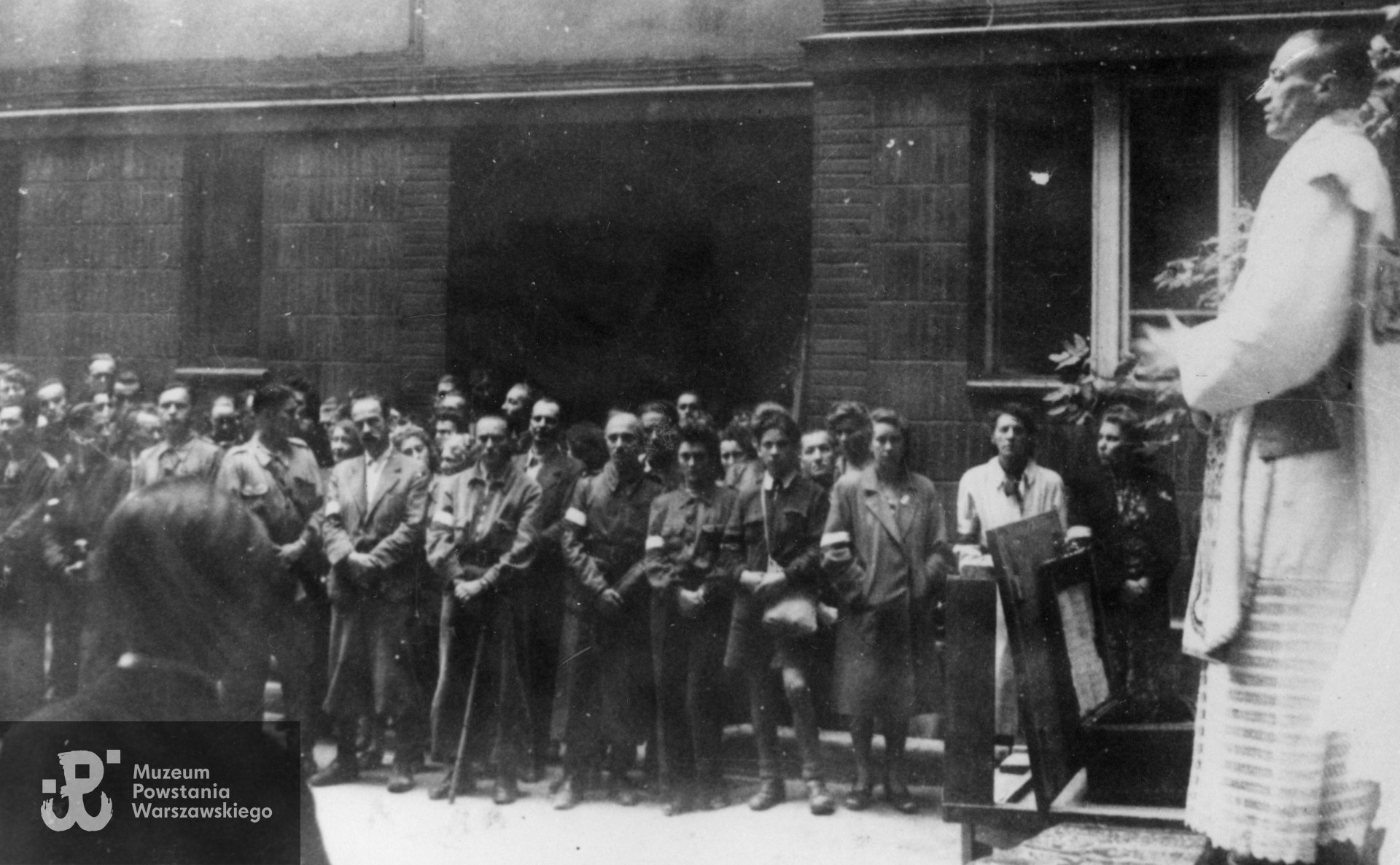 Fotografia z Powstania Warszawskiego wykonana na terenie  Śródmieścia Południe.  Msza św. z okazji Święta Żołnierza 15.08.1944 r. na dziedzińcu domu przy ul. Poznańskiej 12, odprawiona dla żołnierzy bat. Zaremba - Piorun i  żołnierzy VII obwodu "Obroża". Celebruje ks. kapelan Mieczysław Paszkiewicz. Ujęcie tożsame w zbiorach Muzeum Powstania Warszawskiego,  sygn. MPW-IH/4432, MPW-IP/2166. Autorem jest Edward Feliks Wechsler. Zbiory rodzinne, udostępniła   córka, p. Izabela Rola z domu Załoga
