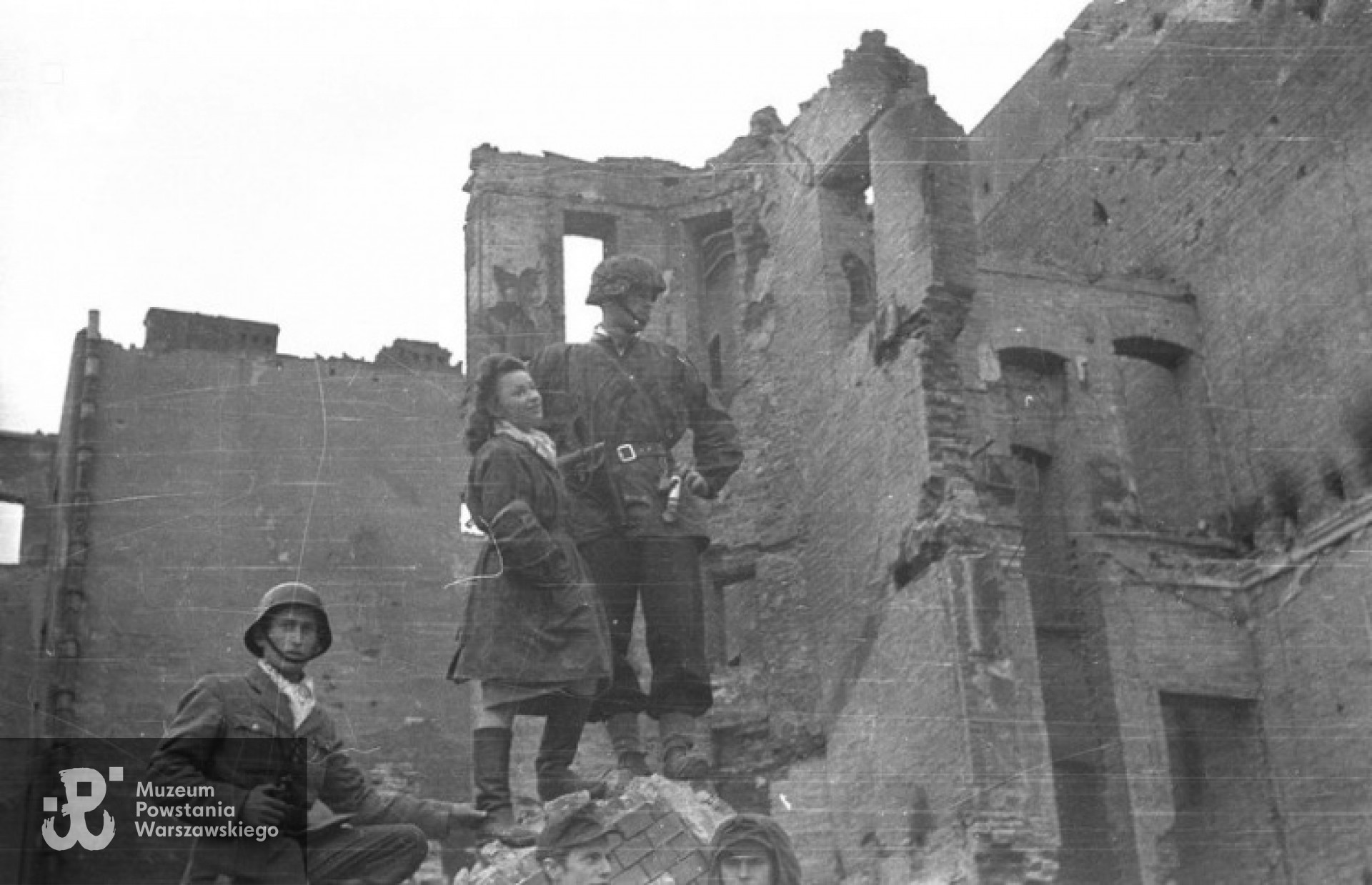 Żołnierze z kompanii "Anna" Batalionu "Gustaw" na ruinach domów przy ulicy Królewskiej. Na wzniesieniu stoją sanitariuszka Henryka Wieczorek "Heniuta" i por. Wiesław Chrzanowski "Wiesław", niżej kpr. Kazimierz Dąb "Kazik". U dołu widoczne częściowo twarze, od lewej: strz. Tadeusza Przybyłowskiego "Romy" i ppor. Henryka Ożarka "Henia"