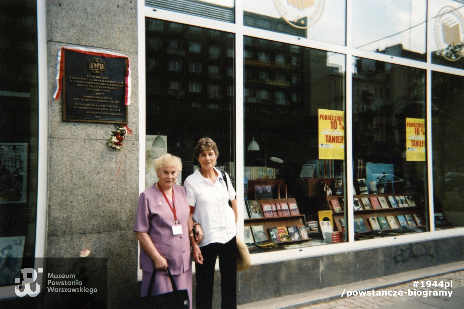 Pani Barbara pod tablicą upamiętniającą batalion znajdującą się na  ścianie budynku przy ul. Marszałkowskiej, w miejscu budynku, w którym mieścił się sztab oddziału. Fot. ze zbiorów prywatnych p. Barbary Wojtanowicz-Włodymirskiej  ps. Ela 