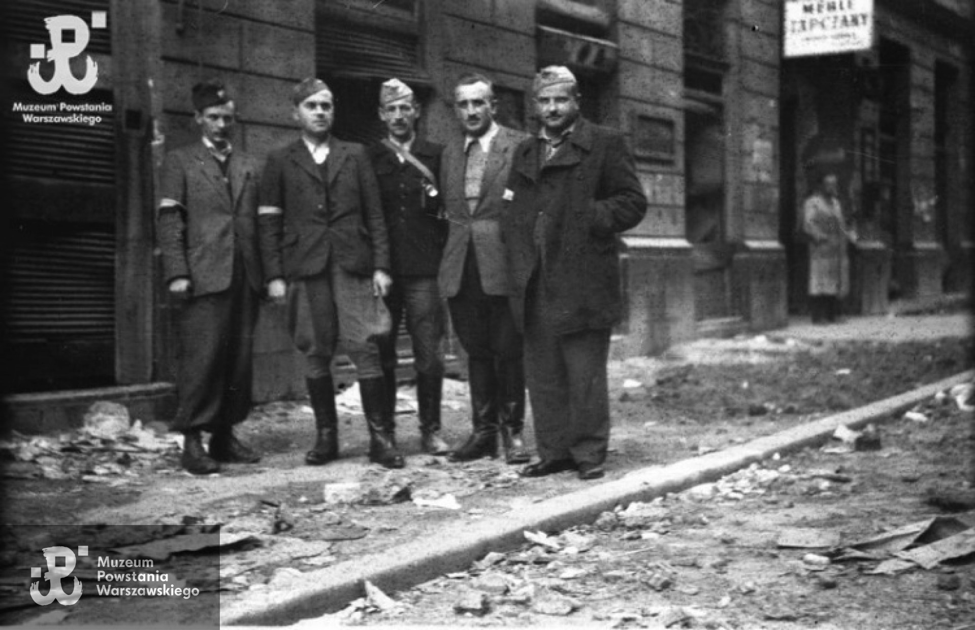 Fotografia z Powstania Warszawskiego. Ul. Złota, vis-a-vis kina "Palladium", Śródmieście Północne. Stoją od lewej: "Żbik", Emil Józef vel Stefan Niemiec "Polaczek", Wacław Loth, "Zygmunt" (lub "Stefan") - właściciel restauracji "Biały Kruk" przy ul. Rysiej, Zdzisław Szymborski "Skowron". Ze zbiorów Fototeki MPW, sygn. MPW-IN/4634