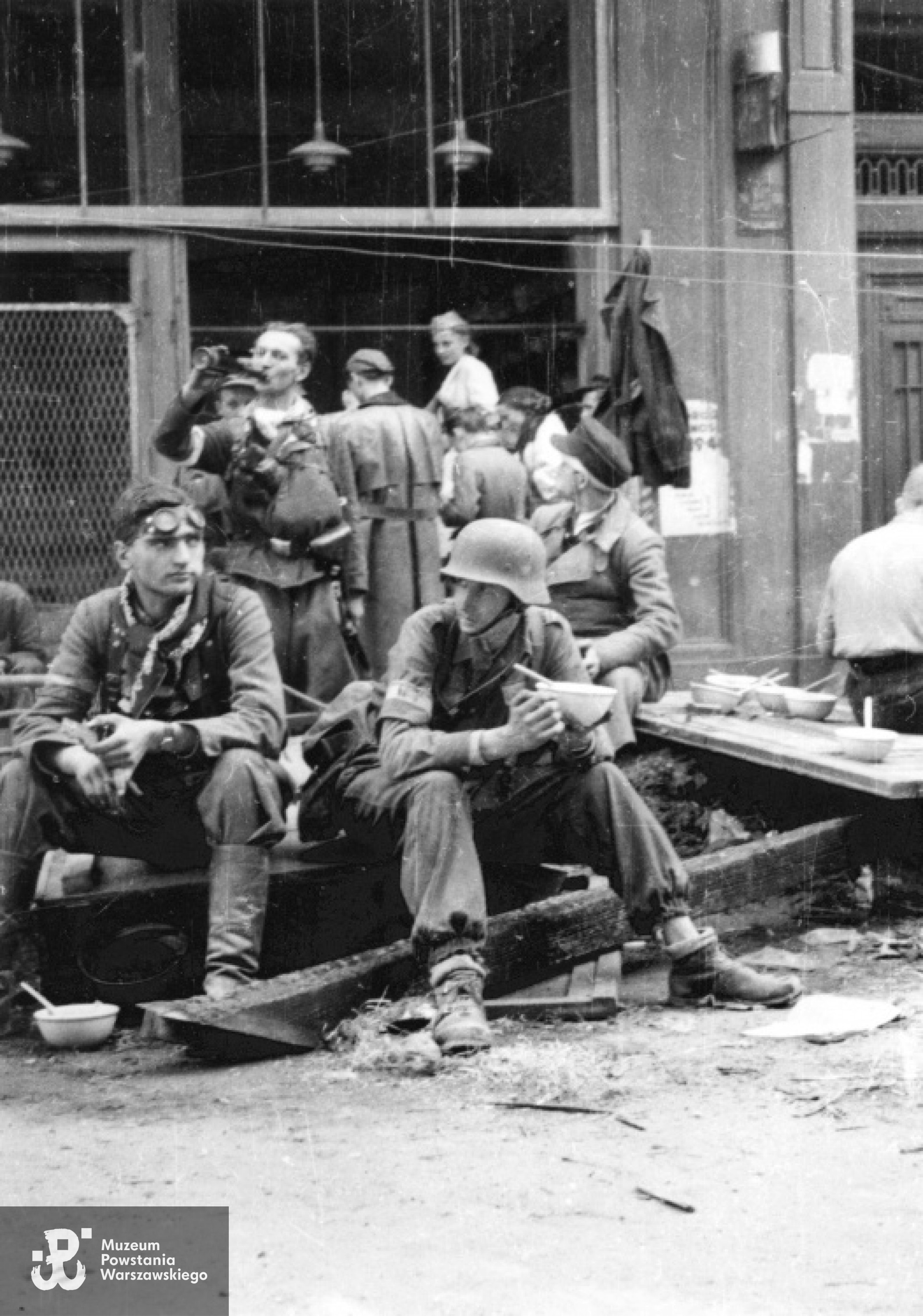 Śródmieście Północne, połowa września 1944 - przerwa na posiłek:  grupa   Powstańców z kompanii "Koszta" odpoczywająca na ulicy Moniuszki; na pierwszym planie od lewej: plut. pchor. Włodzimierz Radajewski ps. Rataj  i kpr. Andrzej Główczewski ps.Marek. Fot. autorstwa Eugeniusza Lokajskiego, zbiory Fototeki MPW, sygn. MPW-IN/496