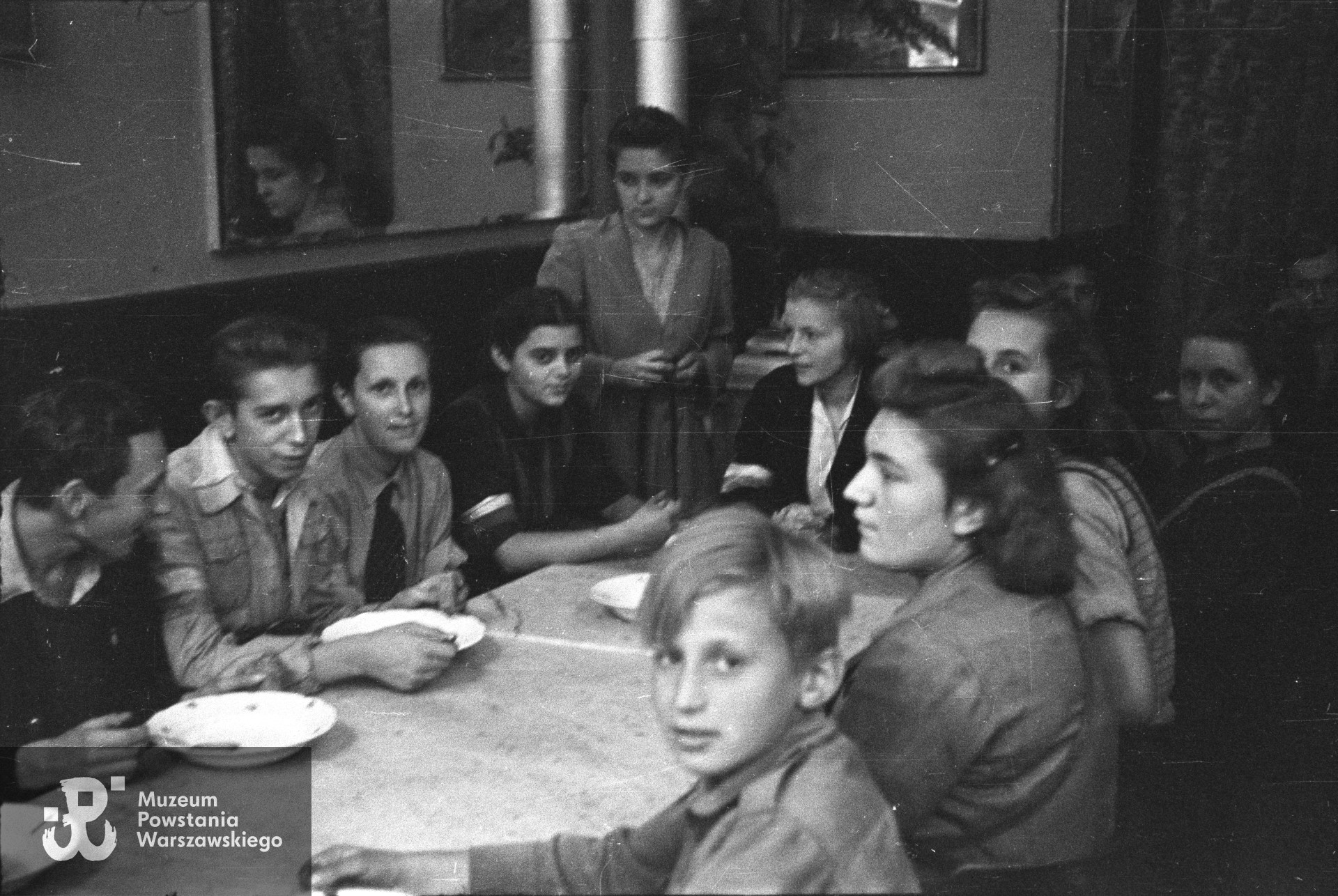  Fotografia  z Powstania Warszawskiego autorstwa Tadeusza Bukowskiego - stanica harcerska przy ul. Wilczej 41. Na pierwszym planie chłopiec siedzący przy stole, zwrócony twarzą do fotografa -  to Tadeusz  Goldmann. Fotografia ukazała się m. in. w 1985 roku w książce Jerzego Kasprzaka „Albatrosa" <i>Tropami powstańczej przesyłki</i> (Wyd. Czytelnik, Warszawa 1985), wówczas p. Tadeusz Goldmann rozpoznał siebie  na zdjęciu. W kolekcji Tadeusza Bukowskiego chłopiec nie jest opisany z imienia i nazwiska. Fot. ze zbiorów Muzeum Powstania Warszawskiego, sygn. MPW-IN/11969