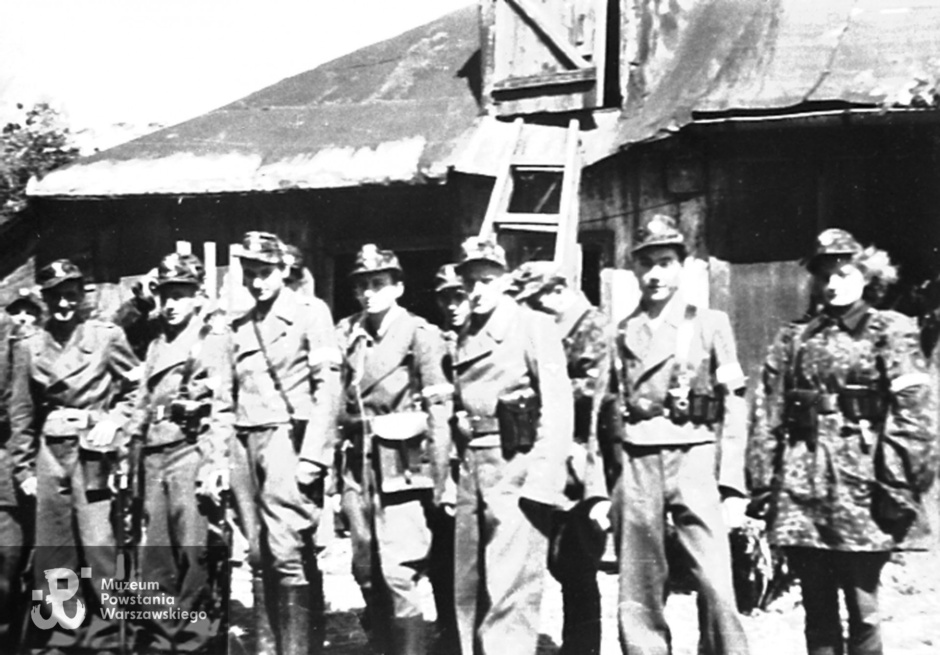 Fotografia z Powstania Warszawskiego. Wola. Żołnierze Zgrupowania "Radosław" w ogrodzie RGO przy ul. Okopowej 41. Jerzy Krzymowski "Jodła" widoczny po lewej.  Fot. ze zbiorów Muzeum Powstania Warszawskiego, sygn. MPW-IH/4224