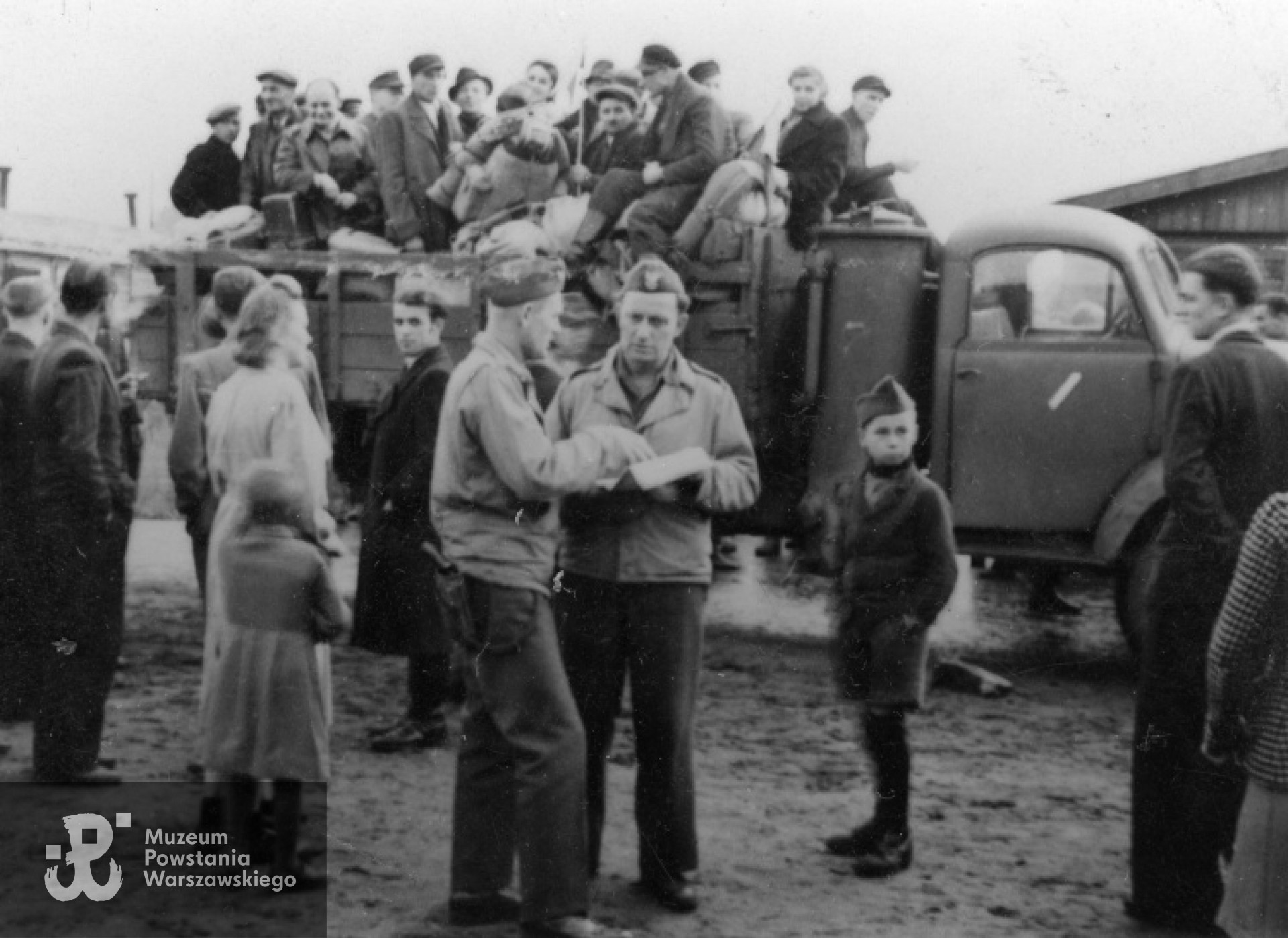 Obóz dla osób powracających z niewoli, koło miasteczka Geesthacht, rok 1945. Anatol Dowgiałło-Chmorowicz, na pierwszym planie stoi bokiem (z pistoletem na prawym biodrze) rozmawia z nierozpoznanym oficerem. Fot. udostępniła p. Bożenna Dowgiałło (Dowgiałło-Chmorowicz)
