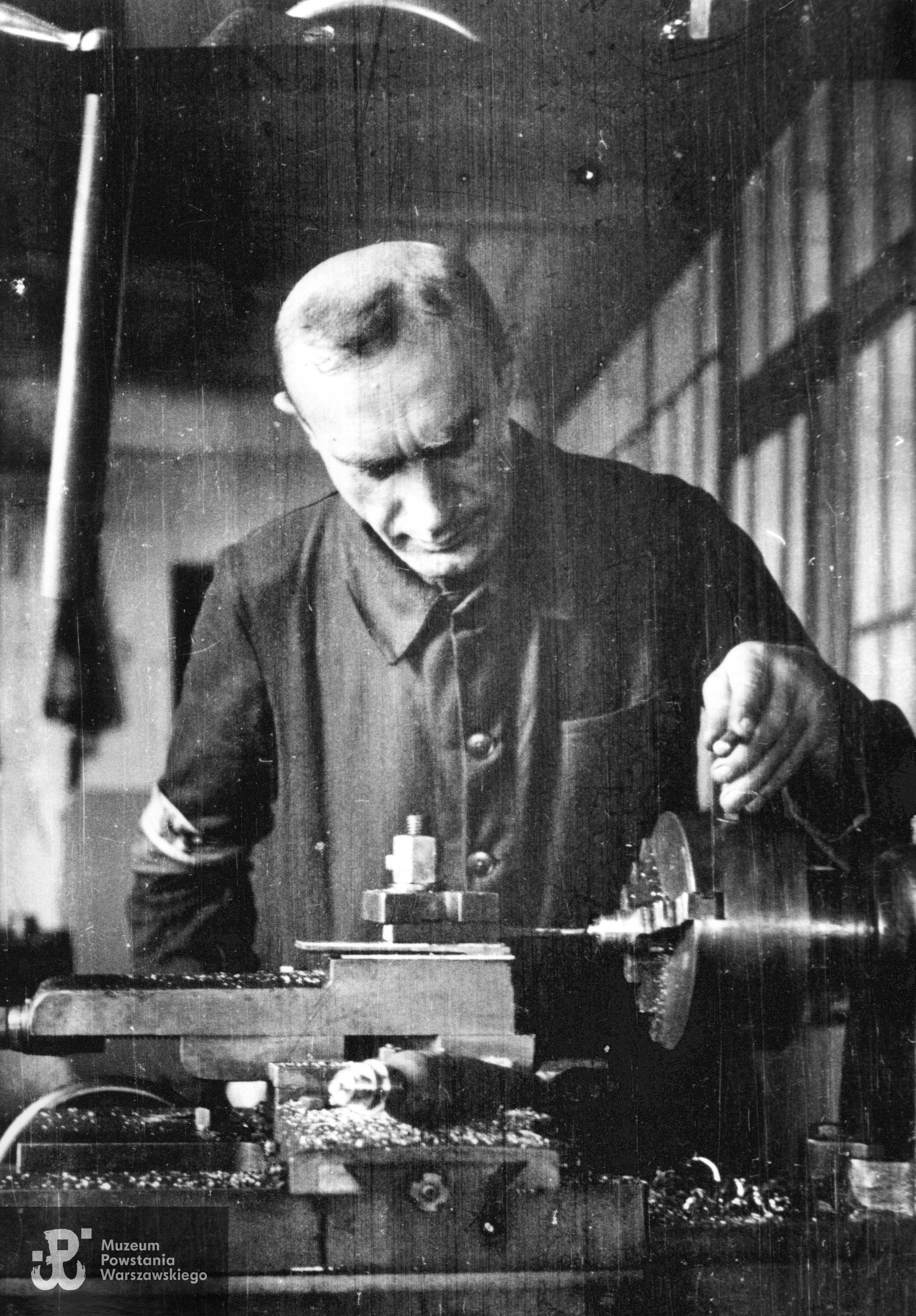 St. wachm. Roch Kafarowski "Ksawery" pracujący przy tokarce w powstańczej wytwórni uzbrojenia. Fot. ze zbiorów Muzeum Powstania Warszawskiego, sygn. MPW-IN/708, autorem zdjęcia jest Eugeniusz Lokajski "Brok". 