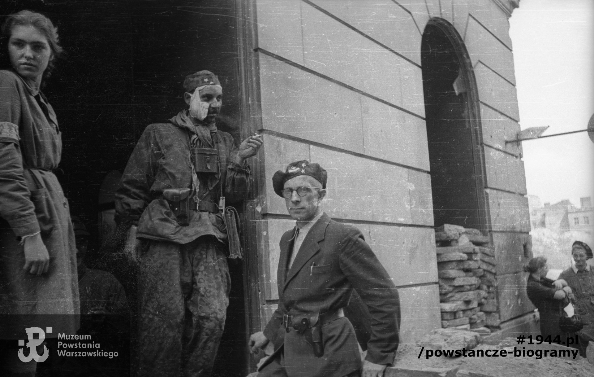 Fotografia z Powstania Warszawskiego autorstwa Joachima Joachimczyka. Śródmieście Północne. Powstańcy ze Starówki stojący po wyjściu z kanałów w bramie kamienicy Mikulskiego przy ul. Nowy Świat 53 od strony ul. Wareckiej. Pierwsza z lewej sanitariuszka Alina Wnuk "Alina". Ze zbiorów Muzeum Powstania Warszawskiego, sygn. MPW-IN/10738