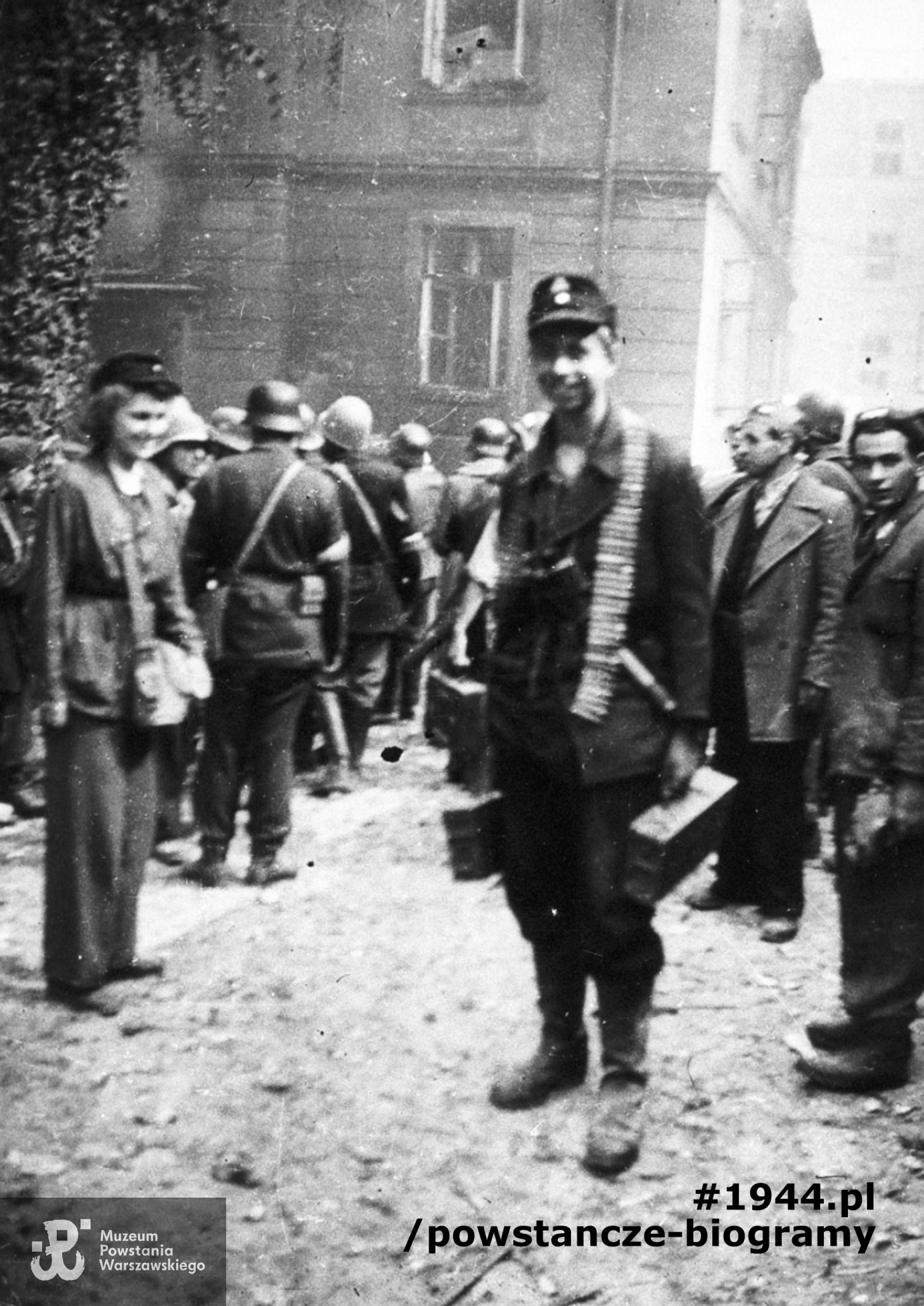 Fotografia z Powstania Warszawskiego. Śródmieście Pónocne. Żołnierz plutonu "Rygla" z 4. kompanii Zgrupowania "Bartkiewicz" na dziedzińcu zdobytej Komendy Policji przy ul. Krakowskie Przedmiescie 1. Na pierwszym planie kpr. pchor. Janusz Sawicki "Zabawa". Ze zbiorów Muzeum Powstania Warszawskiego, sygn. MPW-IH/5467