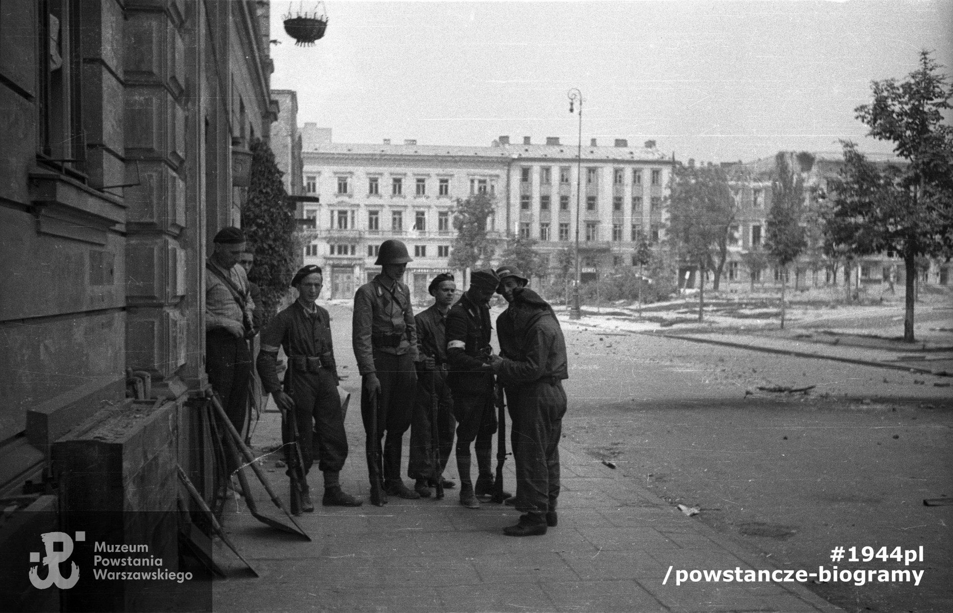 Fotografia z Powstania Warszawskiego autorstwa Joachima Joachimczyka.  Śródmieście Północne. Dowódca plutonu 1150 "Bartkiewicz", por. Władysław Darmosz "Kutno" (trzeci od prawej), wśród swoich żołnierzy przed kwaterą na pl. Dąbrowskiego 5. Ujęcie w kierunku północnym. Ze zbiorów Muzeum Powstania Warszawskiego,  sygn.  MPW-IN/9721 oraz MPW-IP/1060. Na takiej samej fotografii zachowanej w zbiorach rodzinnych kpr. pchor. Józef Rumiński "Spartanin" oznaczony jest jako stojący w pierwszym rzędzie, drugi od lewej (żołnierz patrzący w obiektyw).