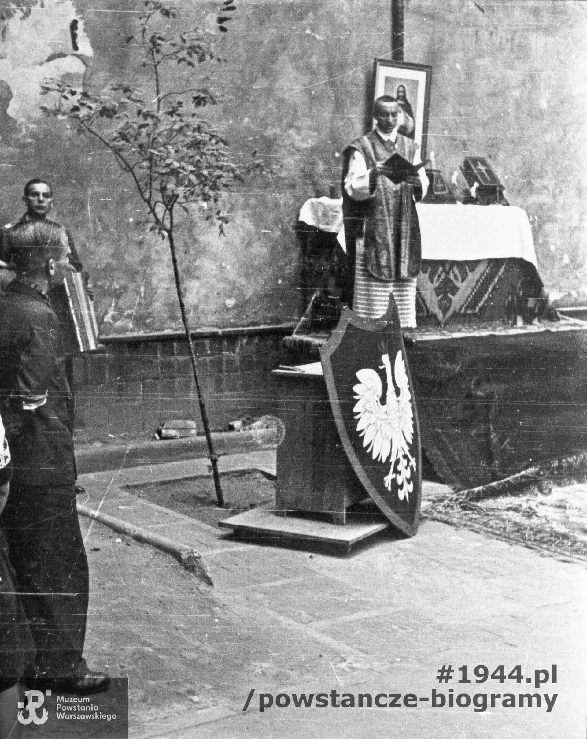 Fotografia z Powstania Warszawskiego. Msza polowa w podwórzu budynku przy ulicy Poznańskiej 12, kwaterze dowództwa zgrupowania "Zaremba" i kompanii "Witolda". Mszę odprawia ksiądz Mieczysław Paszkiewicz. Fot. ze zbiorów Muzeum Powstania Warszawskiego, sygn. MPW-IH/1829