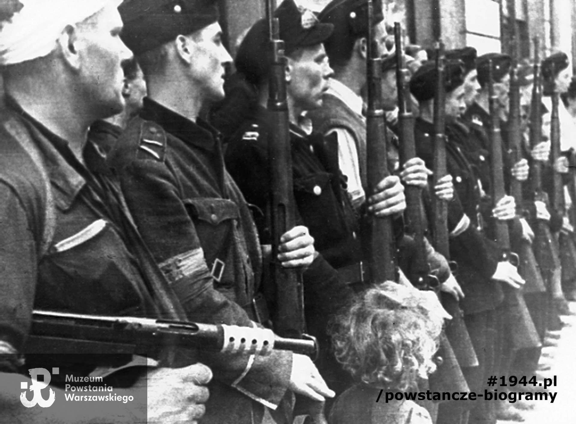 Fotografia z Powstania Warszawskiego. Śródmieście Północne. Pluton honorowy na pogrzebie dowódcy na chodniku pod kamienicą Zgoda 5. Z bandażem na głowie, pierwszy od lewej plut. Henryk Borecki "Smutniak"z plutonu 163, I kompanii "Wigry", Batalionu "Kiliński". Fot. ze zbiorów Muzeum Powstania Warszawskiego, sygn. MPW-IH/4201