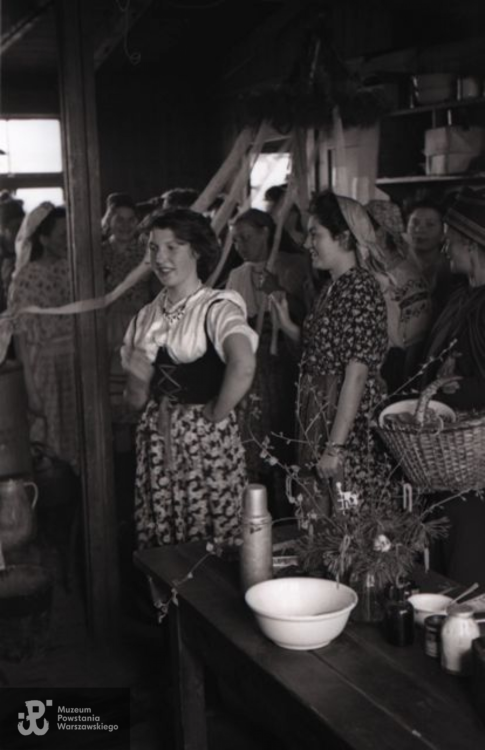 Fotografia ze Stalagu IV B/H Zeithain (obóz szpitalny - oddział Stalagu IV-B Mühlberg).  Dziewczęta przygotowujące się do wielkanocnej ceremonii obnoszenia gaika po obozie. Na pierwszym planie od prawej: Stanisława Mikucka "Sowa", Krystyna Kunowska "Kuna" (zwrócona profilem), Barbara Lewandowska "Wirta". Po prawej w głębi Irena Gabler "Kucia".   Autorem zdjęcia jest Czesław Gerwel "Orłoś". Fot. ze zbiorów Muzeum Powstania Warszawskiego, sygn. MPW-IN/3870