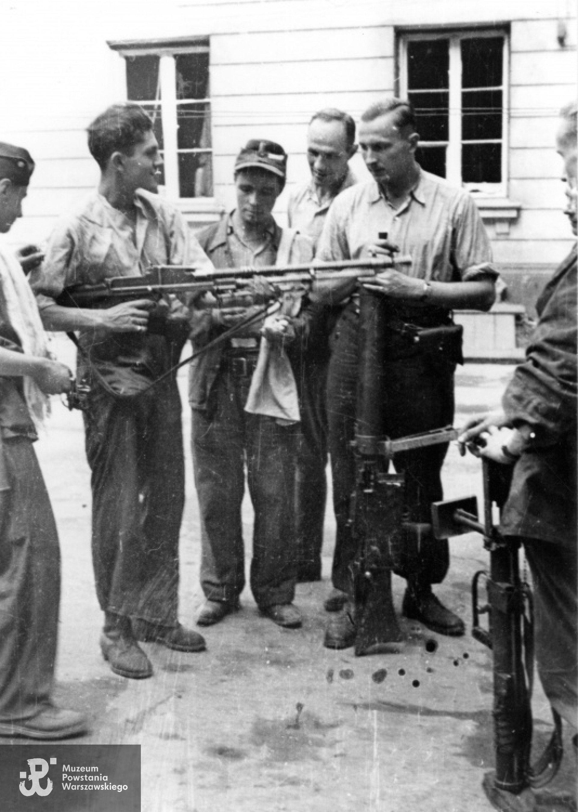Śródmieście Północne. Kpr. pchor. Włodzimierz Wiśniewski "Cygan" z kompanii "Janusza" z Batalionu "Harnaś" pokazujący kolegom ręczny karabin maszynowy Cz Zbrojovka wz. 26 ze zrzutu. Po prawej stoi plut. pchor. Adam Podkóliński "Michał" (w jasnej koszuli) z opartym o ziemię niemieckim lekkim karabinem maszynowym - leMG 08/15. Fotografia  autorstwa Eugeniusza Lokajskiego, prawa autorskie: MPW. Zbiory Fototeki MPW, sygn. MPW-IN/728