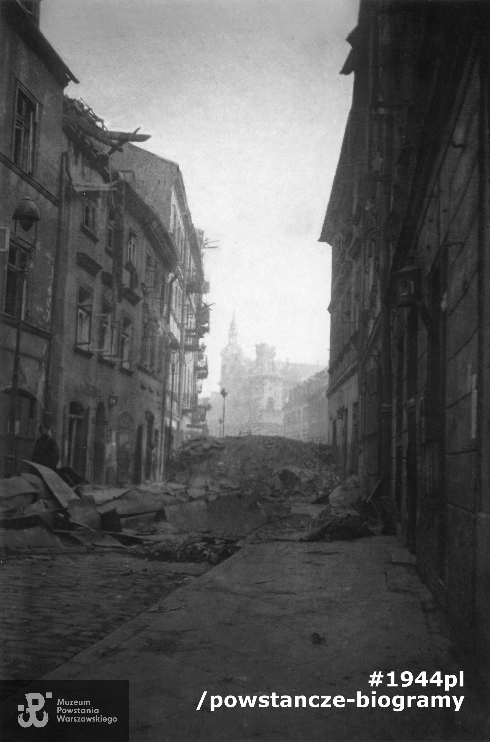 Fotografia z Powstania Warszawskiego. Zdjęcie wykonane przez p. Ryszarda Krokwę w dniach 19-21.08.1944 przedstawiające fragment ulicy Freta z widoczną barykadą u zbiegu  ul. Freta i Świętojerskiej. Na dalszym planie widać   płonący kościół oo. Paulinów. Fot. ze zbiorów Muzeum Powstania Warszawskiego, sygn.  MPW-IN/4659, dar Ryszarda Krokwy