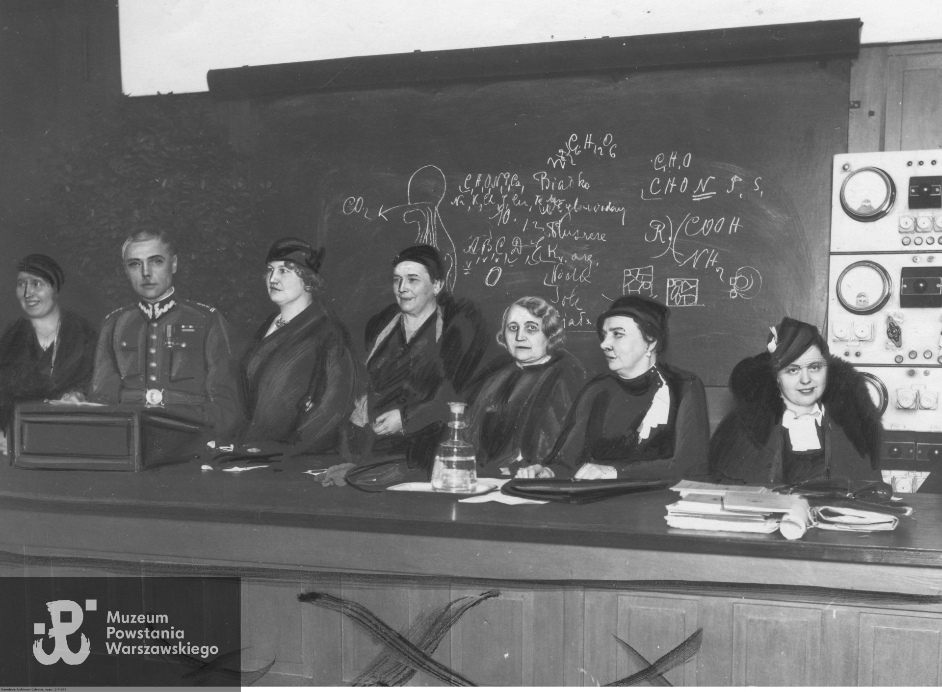 1934 rok - Prezydium zjazdu członków Związku Pań Domu w Poznaniu. Od lewej widoczni: Gertruda Dobrowolska, płk. Teofil Kucharski, Maria Roman, Maria Szczaniecka, Kamila Nitsch, Wanda Ładzina i Jadwiga Roman. Fot. ze zbiorów Narodowego Archiwum Cyfrowego - Koncern Ilustrowany Kurier Codzienny - Archiwum Ilustracji, www.audiovis.nac.gov.pl