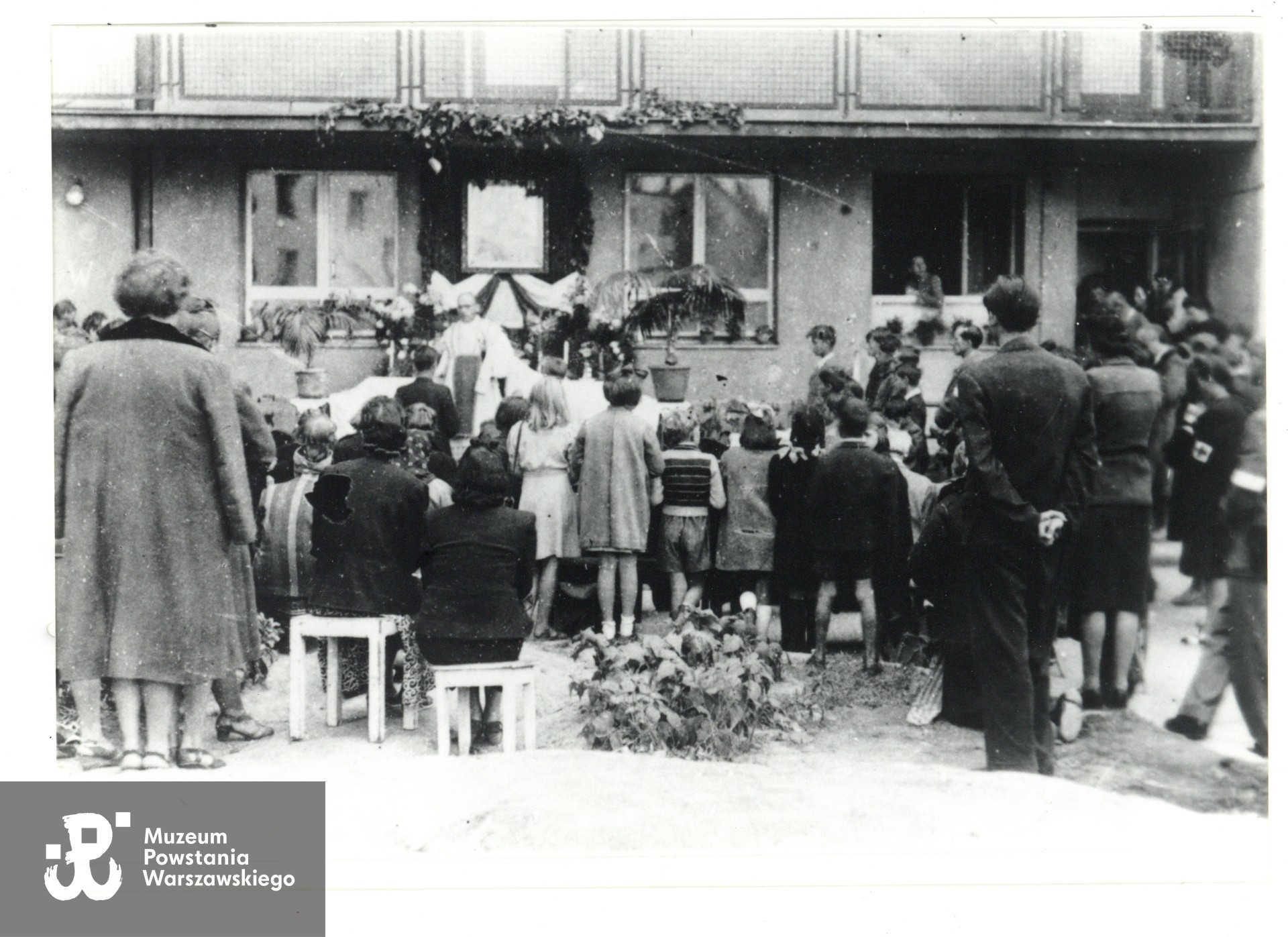 Fotografia z Powstania Warszawskiego. Sierpień 1944 r.,  msza św. polowa odprawiana na podwórku bloku przy ul. Mickiewicza 25.  Fot. ze zbiorów Muzeum Powstania Warszawskiego, dar p. Zbigniewa Chmielewskiego.