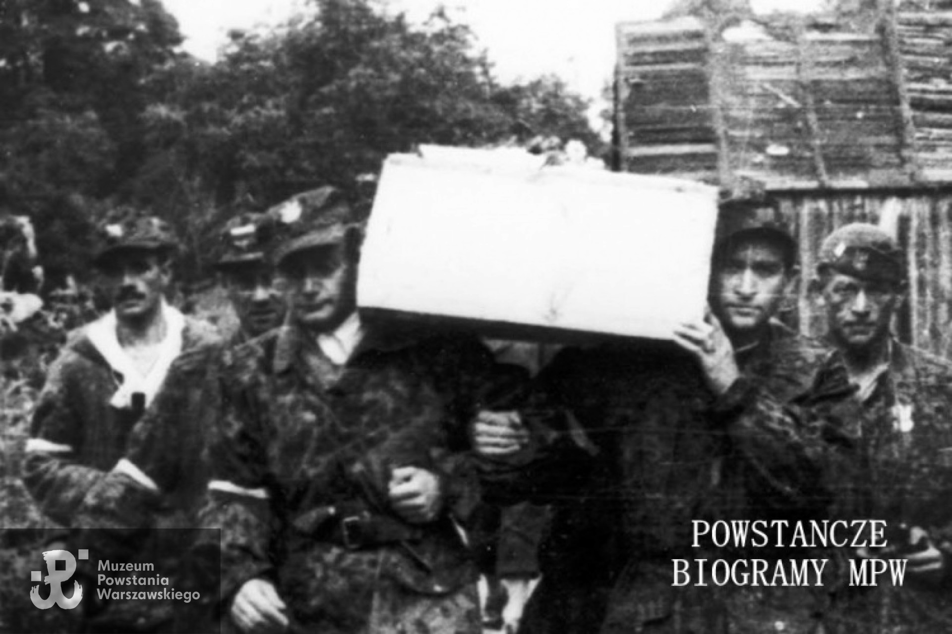Powiększony fragment zdjęcia z poprzedniej strony: trumnę niosą ppor. Kazimierz Barszczewicz "Henryk" i ppor. NN "Ryś". Z lewej widoczny ppor. Jan Kowalczyk "Kieł", z lornetką po prawej Eugeniusz Kuźwa "Hipek" dowódca 169 plutonu batalionu "Kiliński". Autorem zdjęcia jest Stefan Bałuk. Fot. ze zbiorów Muzeum Powstania Warszawskiego, sygn.   MPW-IS/149. Ujęcie tożsame: MPW-IH/3444.