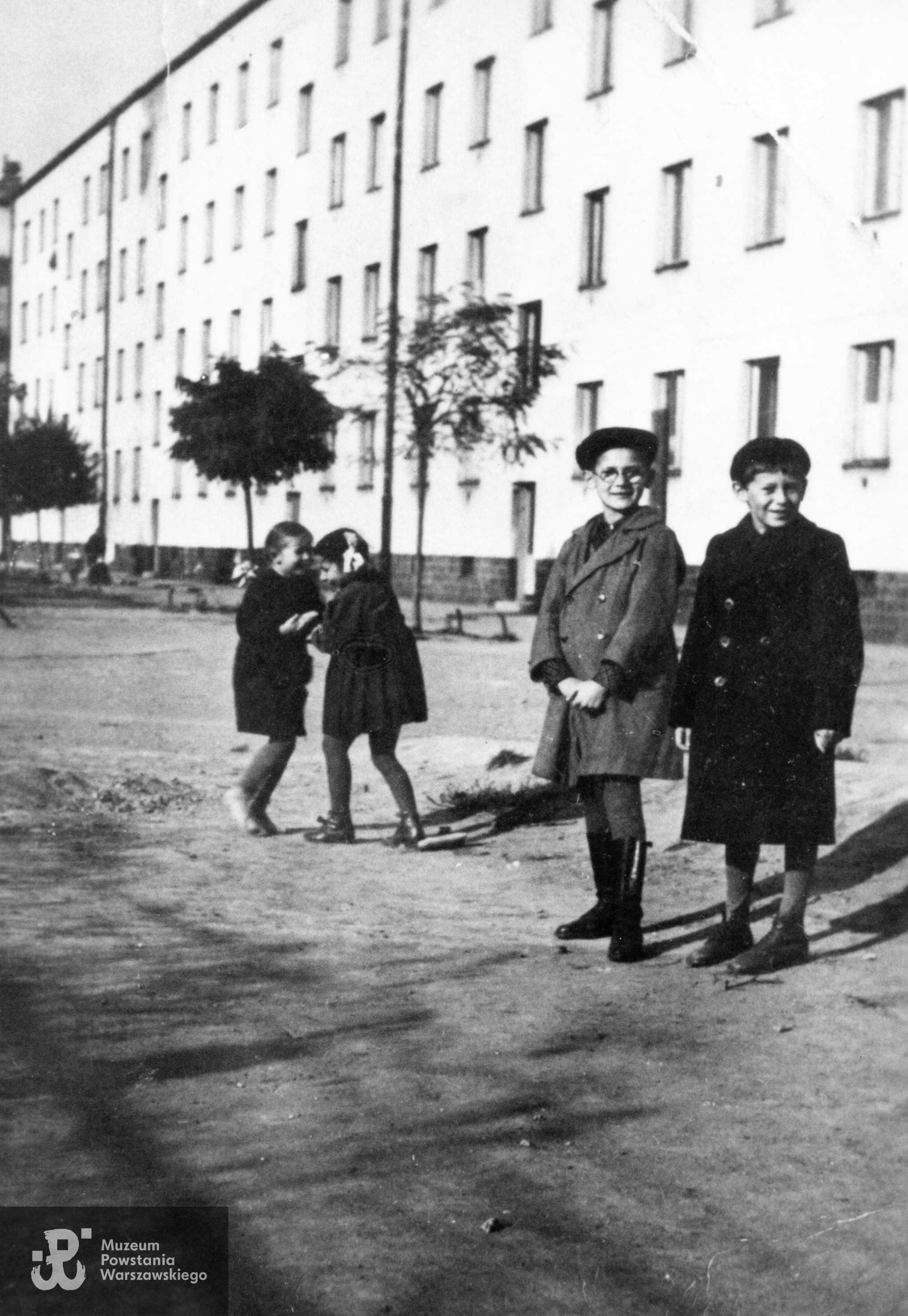  Fotografia z okresu okupacji niemieckiej wykonana wiosną 1940 roku na Żoliborzu, przedstawiająca dzieci  bawiące się na podwórku przy bloku na ul. Mickiewicza 25. Na pierwszym planie widoczny 9-letni Andrzej Chmielewski (w okularach) z kolegą z podwórka, w głębi młodsza siostra Andrzeja, wówczas 6-letnia Basia Chmielewska (z prawej, z kokardą we włosach) z koleżanką.  Rodzina pp. Chmielewskich (rodzice Stanisław i Janina z dziećmi Andrzejem i Barbarą) mieszkała na parterze domu przy Mickiewicza 25 pod numerem 88. Fot. ze zbiorów prywatnych p. Zbigniewa Chmielewskiego.
