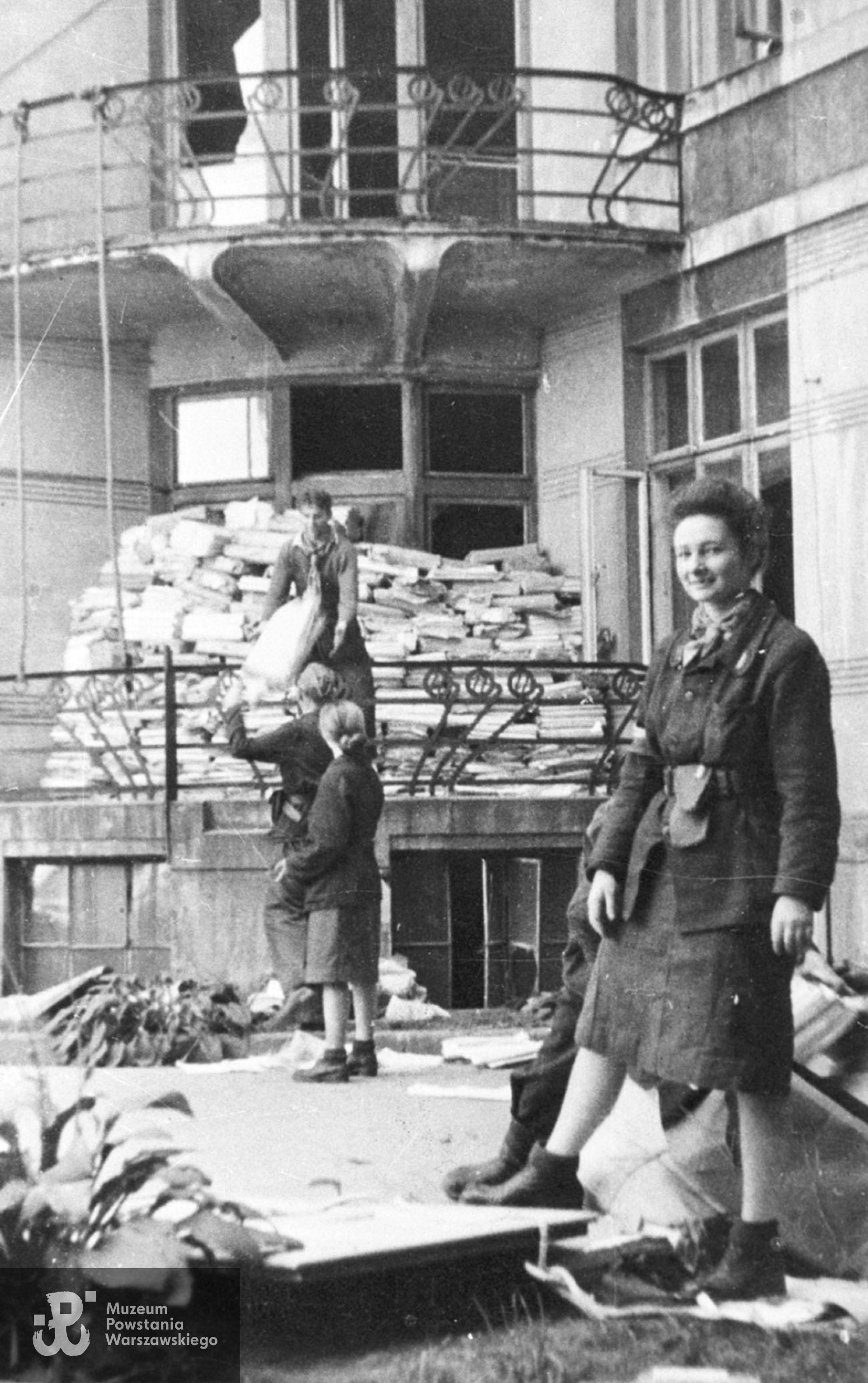 Fotografia z Powstania Warszawskiego autorstwa Bernarda Marwińskiego (PSW), przedstawiająca stanowisko strzeleckie na balkonie budynku Gimnazjum Męskiego im. Jana Zamoyskiego przy Smolnej 30 kamienicy, umacniane za pomocą paczek z papierem. Fot. ze zbiorów Muzeum Powstania Warszawskiego, sygn. MPW-IH/4401