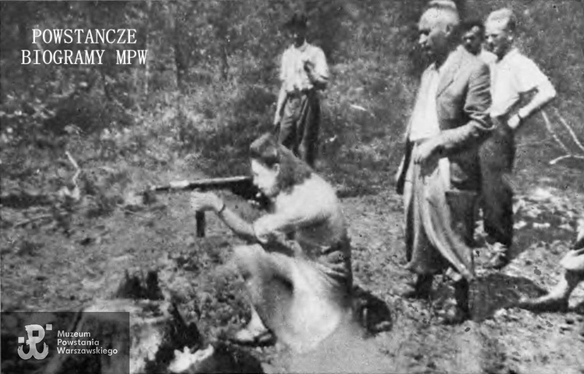 Przestrzeliwanie prototypu pistoletu maszynowego "Błyskawica" na strzelnicy w Puszczy Kampinoskiej wiosną 1944 roku. Rozpoznane osoby: strzela łączniczka dowódcy batalionu "Zośka" ppor. Maria Janina Całka "Wika", na dalszym planie, w koszuli, podparty Kmita, na ostatnim planie, w środku Strzegon. Zdjęcie  opublikowane w magazynie "Stolica", nr 30 z 1958 roku w artykule Henryka Pawła Kozłowskiego. Udostępnił Dariusz Zawrotny.