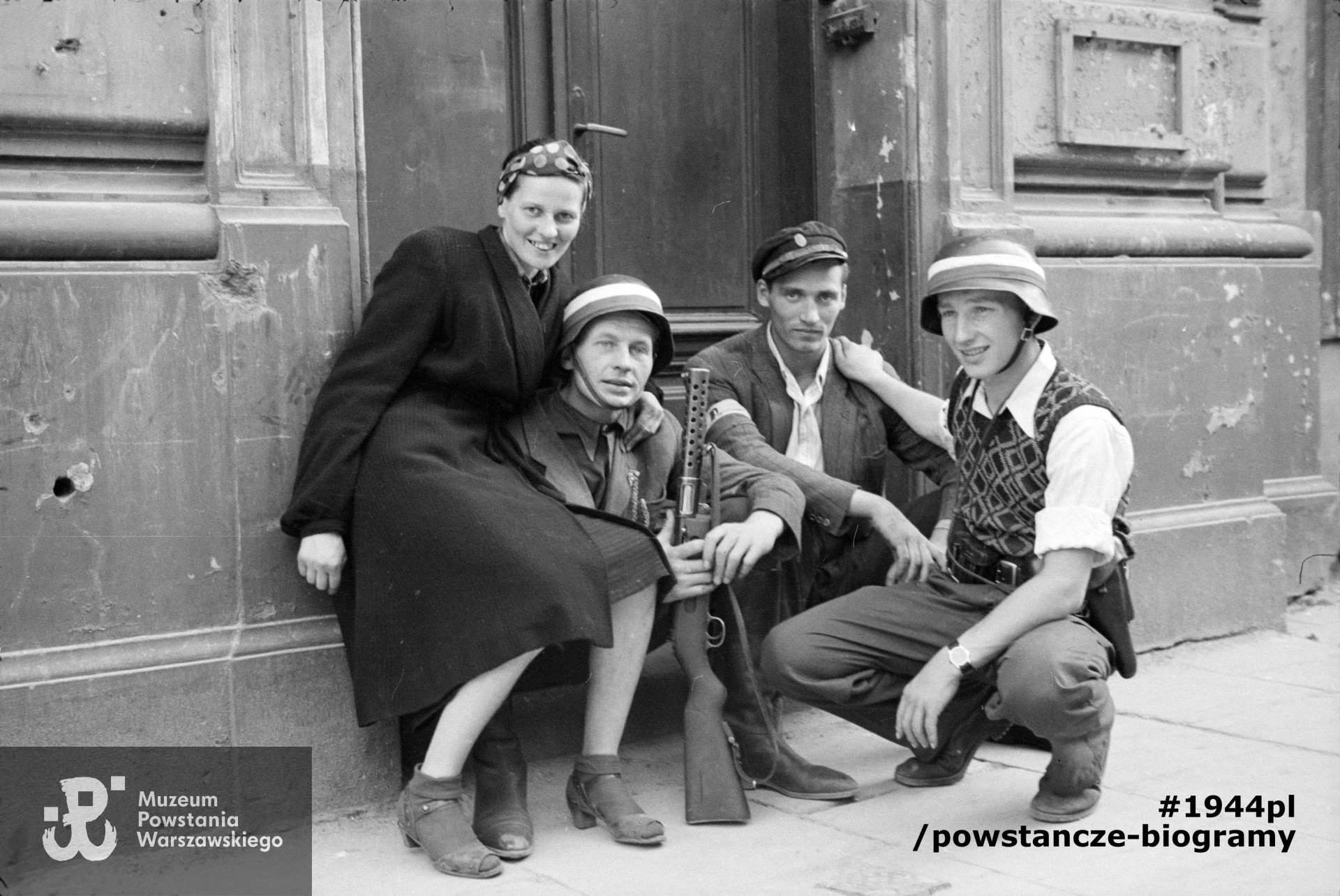 Fotografia z Powstania Warszawskiego. Śródmieście Północne. Grupa Powstańców z kompanii "Koszta" przy bocznym wejściu do gmachu Filharmonii przy ul. Jasnej 5. Od lewej: Zofia Domańska "Zocha" (siostra autora zdjęć), por. Roman Rozmiłowski "Zawada" trzymający niemiecki zdobyczny pistolet maszynowy MP 28 II "bergmann", ppor. Stanisław Kuśpit "Kruk" i kpr. pchor. Antoni Tuleja "Niedźwiedź". Autorem zdjęcia jest Eugeniusz Lokajski. Fot. ze zbiorów Muzeum Powstania Warszawskiego, sygn. MPW-IN/44