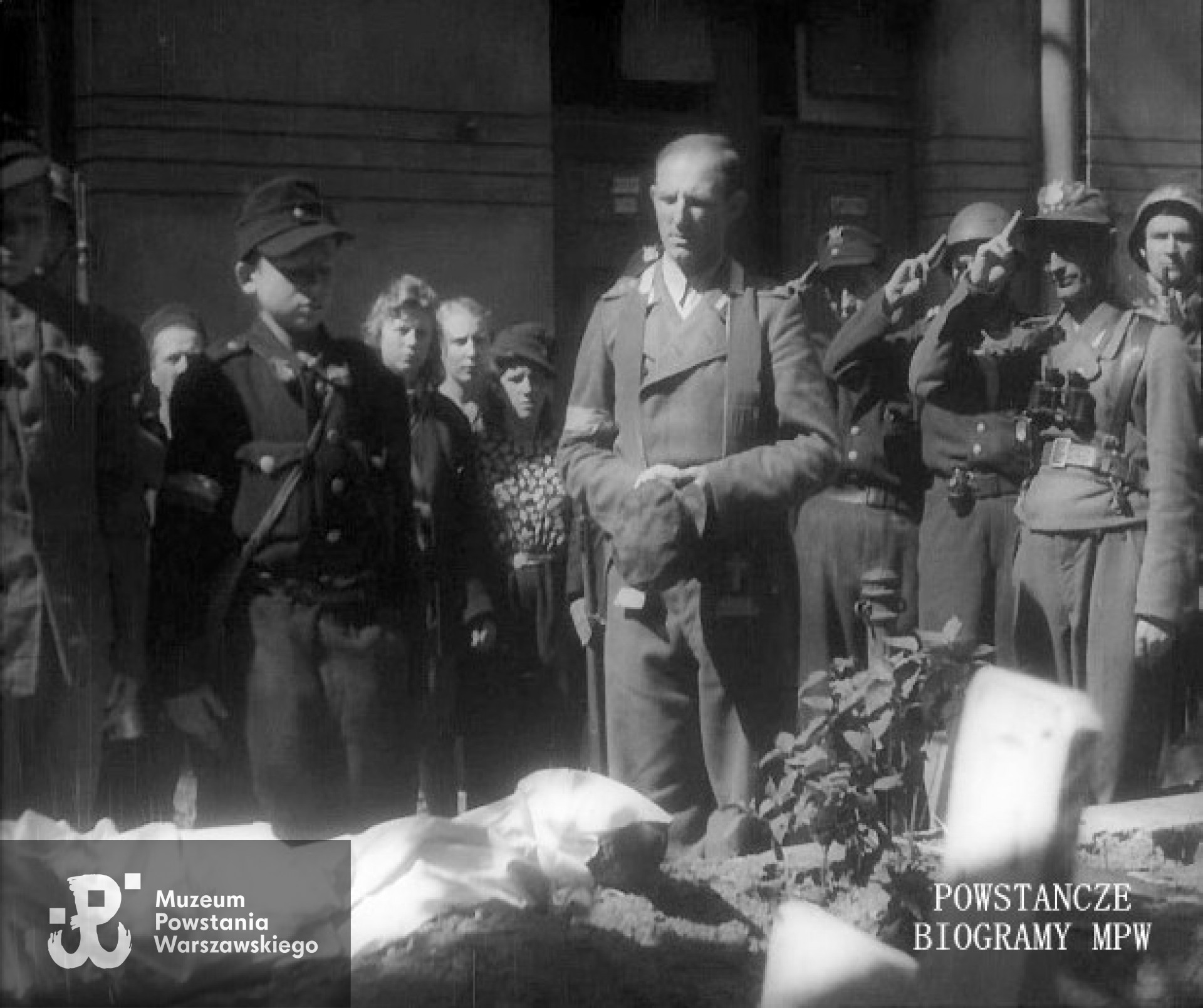 Podwórze domu przy ulicy Ceglanej 3. Ksiądz mjr Władysław Zbłowski „Struś” prowadzi ceremonię pochówku Wojciecha Zalewskiego „Orła Białego”. Panorama na dwuszereg żołnierzy prezentujących broń. Na pierwszym planie w czarnej czapce i kombinezonie Jerzy Wysocki „Mewa”, kolega „Orła Białego”. Panorama w dół na otwartą mogiłę i ciało łącznika. Z prawej z lornetką na piersi salutujący kpt. Wacław Stykowski „Hal”, za nim Mieczysław Mirecki "Błyskawica" Kadr powstańczej kroniki [powstaniewarszawskiefilm.pl / MPW]
