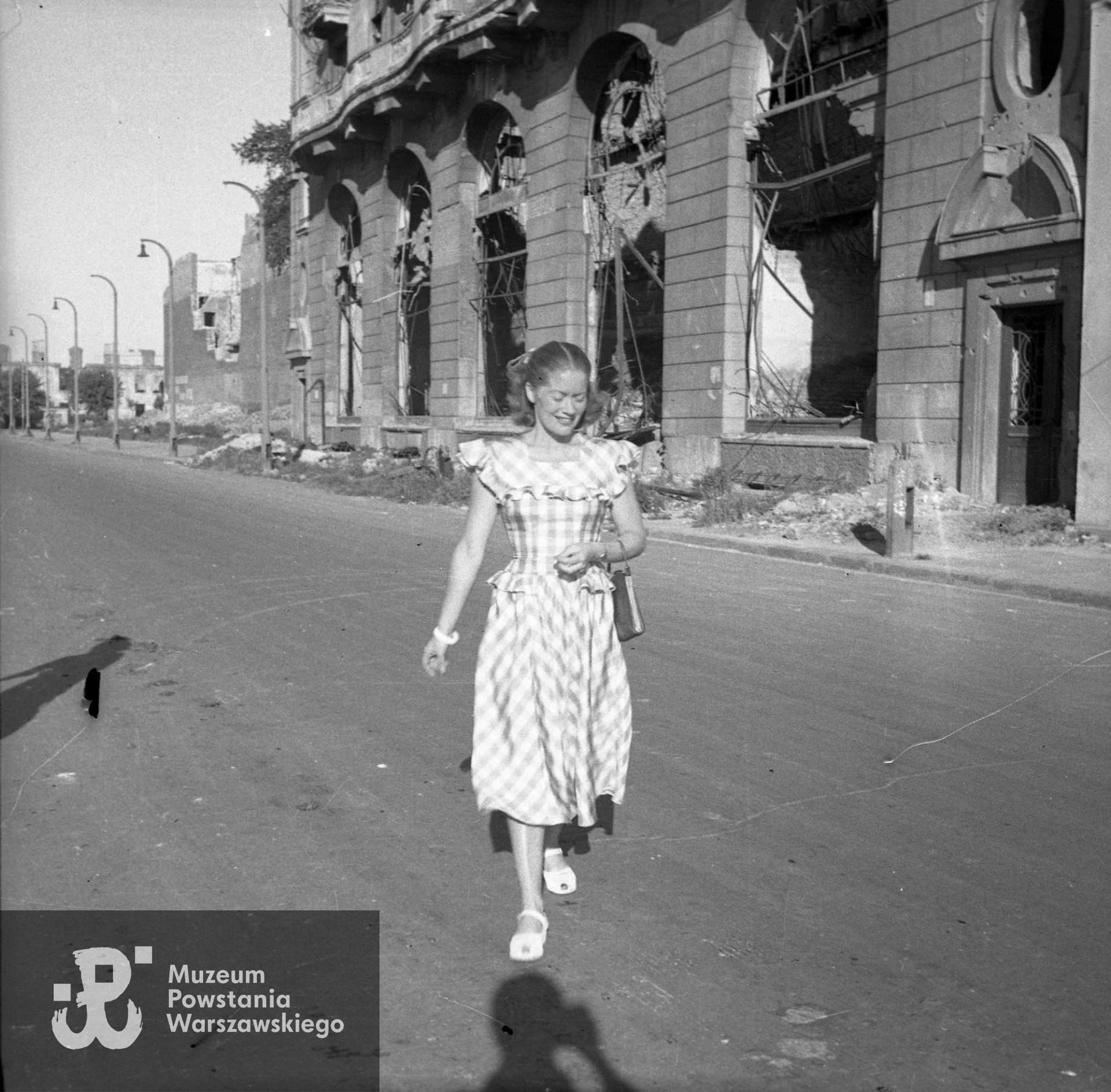 Fotografia  wykonana w Warszawie po jej wyzwoleniu. Śródmieście Południowe. Aktorka Alina Janowska (w Powstaniu Warszawskim łączniczka "Alina" w batalionie "Kiliński") w Alei Józefa Piłsudskiego (po wojnie Armii Ludowej), ujęcie od ulicy Polnej w stronę Marszałkowskiej.Autorem zdjęcia jest Edward Dziewoński. Fot. ze zbiorów Muzeum Powstania Warszawskiego, sygn. MPW-IN/4232