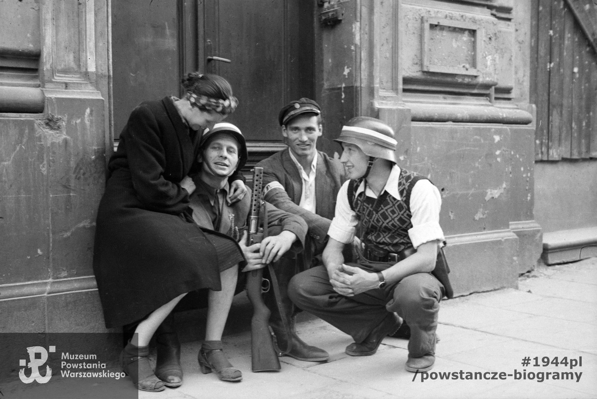 Fotografia z Powstania Warszawskiego. Śródmieście Północne. Grupa Powstańców z kompanii "Koszta" przy bocznym wejściu do gmachu Filharmonii przy ul. Jasnej 5. Od lewej: Zofia Domańska "Zocha" (siostra autora zdjęć), por. Roman Rozmiłowski "Zawada", trzymający niemiecki zdobyczny pistolet maszynowy MP 28 II "bergmann", ppor. Stanisław Kuśpit "Kruk" i kpr. pchor. Antoni Tuleja "Niedźwiedź". Autorem zdjęcia jest  Eugeniusz Lokajski "Brok". Ze zbiorów Muzeum Powstania Warszawskiego, sygn.  MPW-IN/42