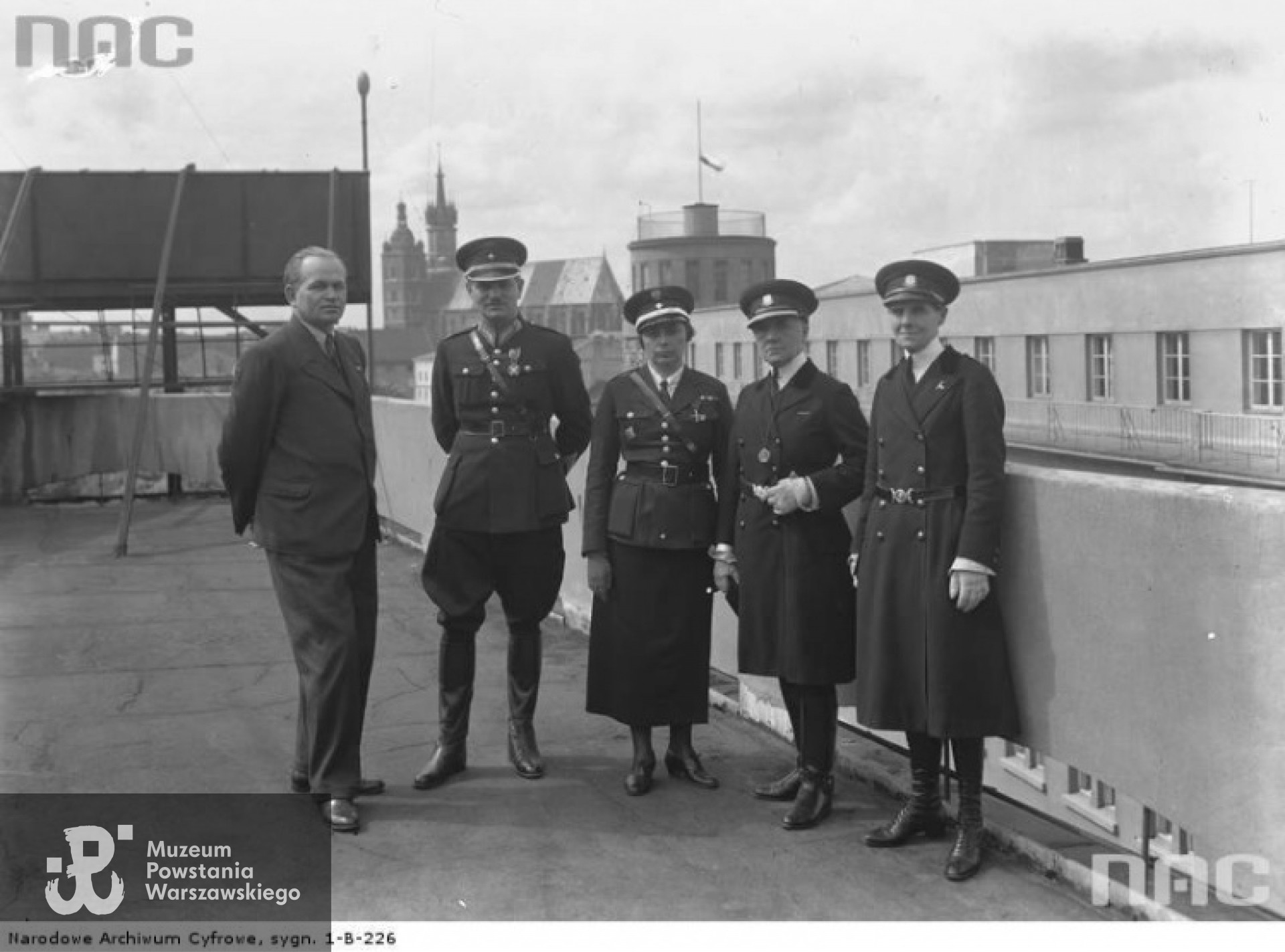 Wizyta przedstawicielek angielskiej policji kobiecej w Krakowie: policjantki angielskie na dachu krakowskiego Pałacu Prasy - maj 1935 roku. Widoczne m.in.: komendantka angielskiej policji kobiecej Mary Allen (II z prawej), inspektor policji kobiecej Taggart (I z prawej) W środku stoi  podkomisarz Stanisława Paleolog (III z prawej). Fot. ze zbiorów NAC [www.audiovis.nac.gov.pl]