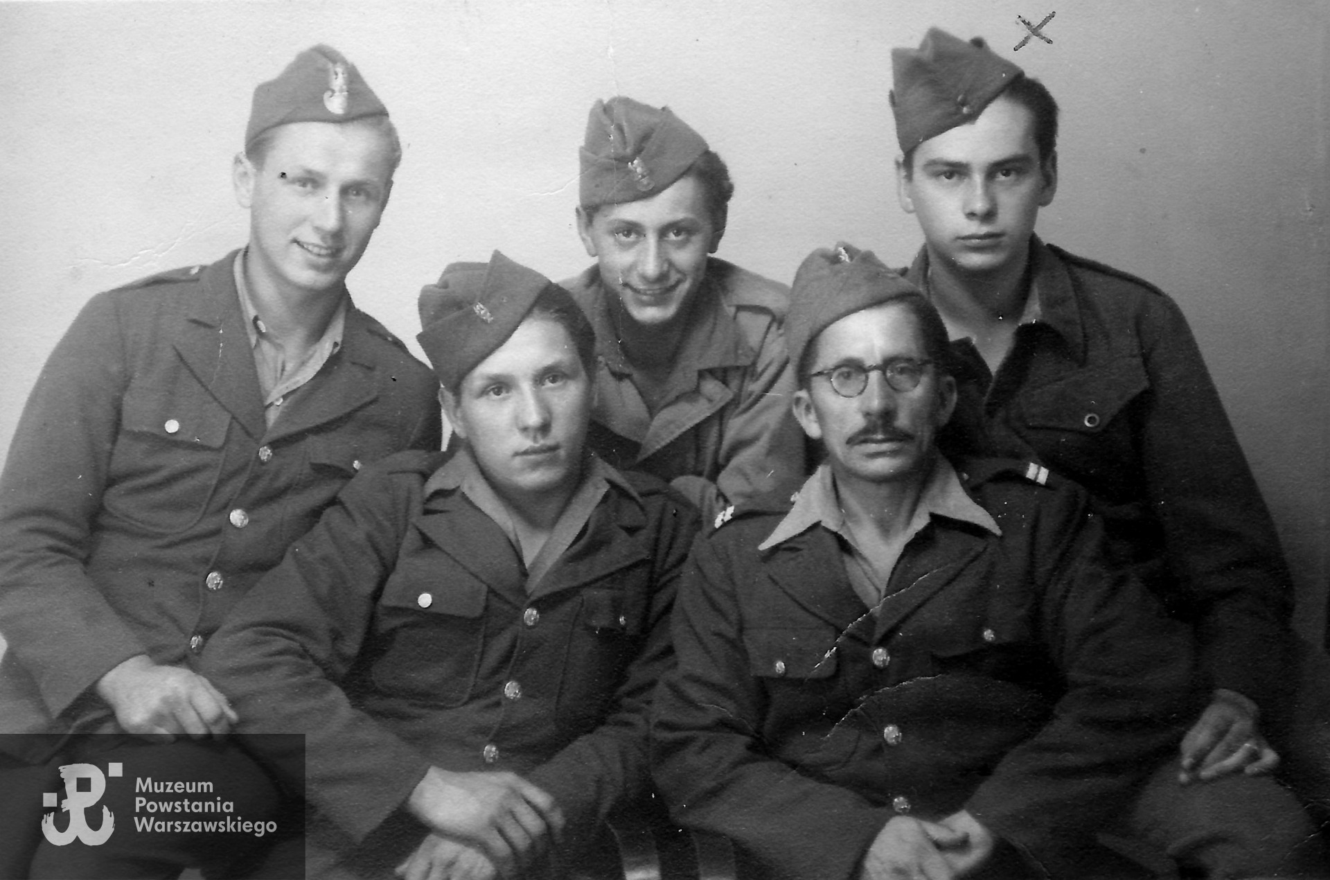 Fotografia wykonana w Northeim (Dolna Saksonia, Niemcy), dn. 27.06.1945 r.   W drugim rzędzie  pierwszy z prawej strony (znaznaczony „x”) stoi Ryszard Szymczak ps. Czarny, przed  nim kpr. Walenty Danis „Zenon". W drugim rzędzie z tyłu drugi od prawej stoi za ojcem strz. Mieczysław Danis ps. Olgierd. Fot. ze zbiorów rodzinnych p. Mirosława Szymczaka. Skany wykonano w Muzeum Powstania Warszawskiego, 12/2022.