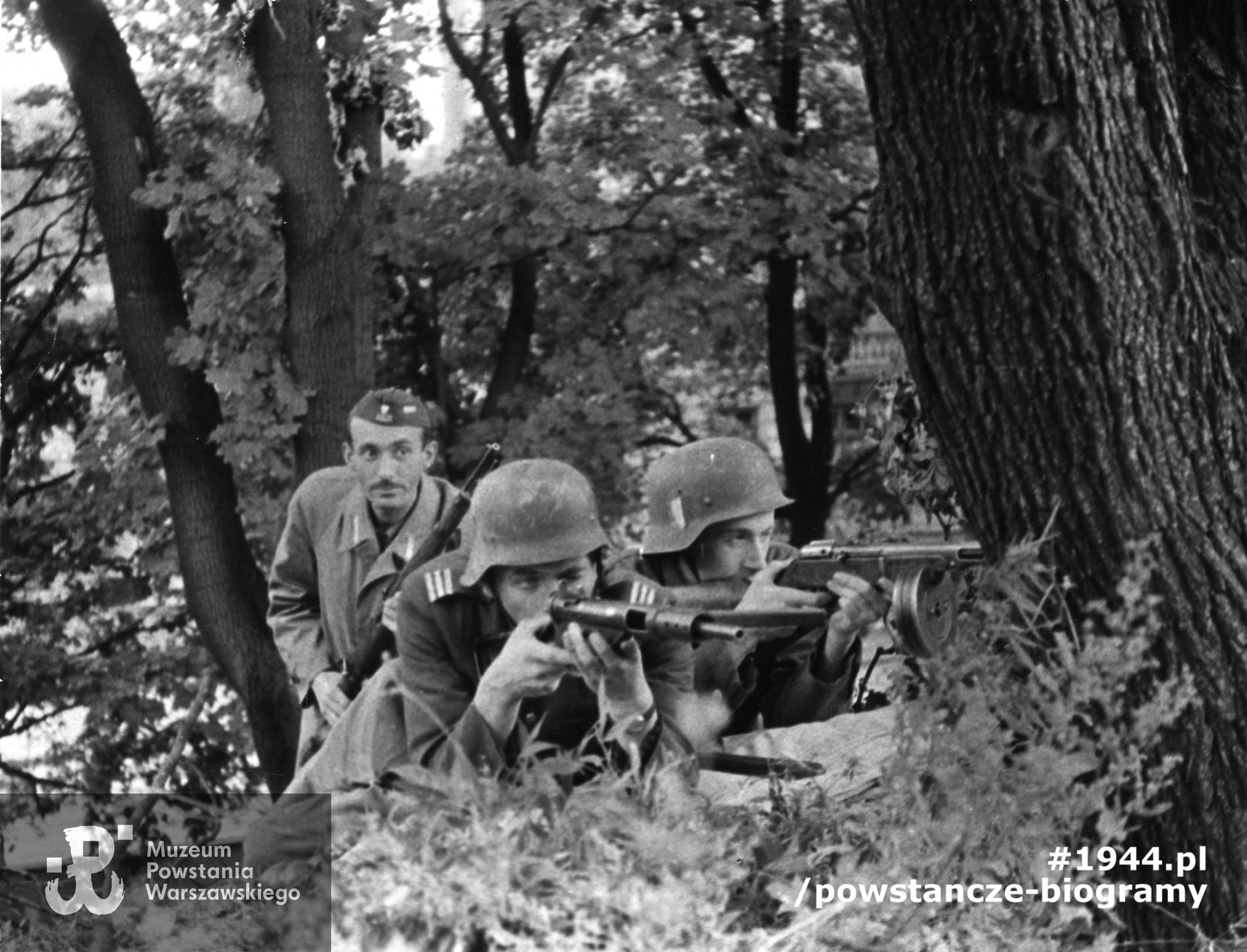 Fotografia z Powstania Warszawskiego. Śródmieście Południowe. Stanowisko strzeleckie na skarpie w ogrodzie szpitala św. Łazarza. Na pierwszym planie powstańcy z batalionu "Miłosz", od lewej: plut. Ryszard Lewandowski "Oporek" z brytyjskim pistoletem maszynowym Sten MkII, obok kpr. Lech Krasnowolski "Leszek" z sowieckim pistoletem maszynowym PPSz wz. 1941, z tyłu (w furażerce) Wacław Paradowski "Kary" z karabinem Mauser wz. 1898k. Fot. ze zbiorów Muzeum Powstania Warszawskiego, sygn. MPW-IK/2403. Autorem zdjęcia jest Wojciech Marczyński "Bogusław"
