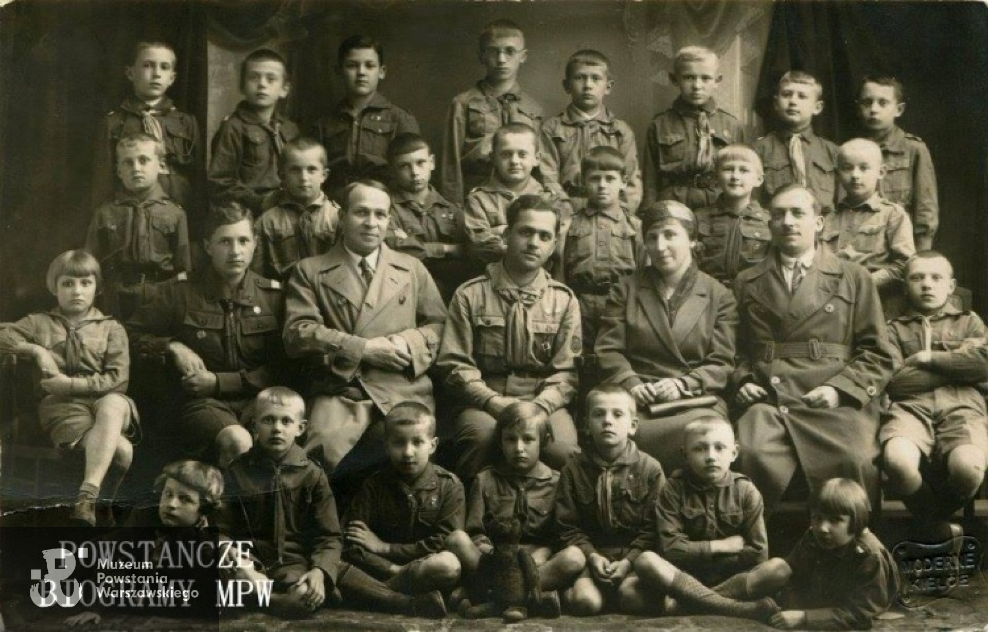 Na fotografii 1. Kielecka Drużyna Harcerzy - równocześnie pierwsza drużyna w tym regionie kraju. Bogdan Dąbrowski  siedzi trzeci od lewej. Za nim, w płaszczu jego ojciec, Józef Dąbrowski, prokurent Banku Polskiego. Fot. z archiwum rodzinnego udostępnione przez p. Annę i Andrzeja Dąbrowskich.