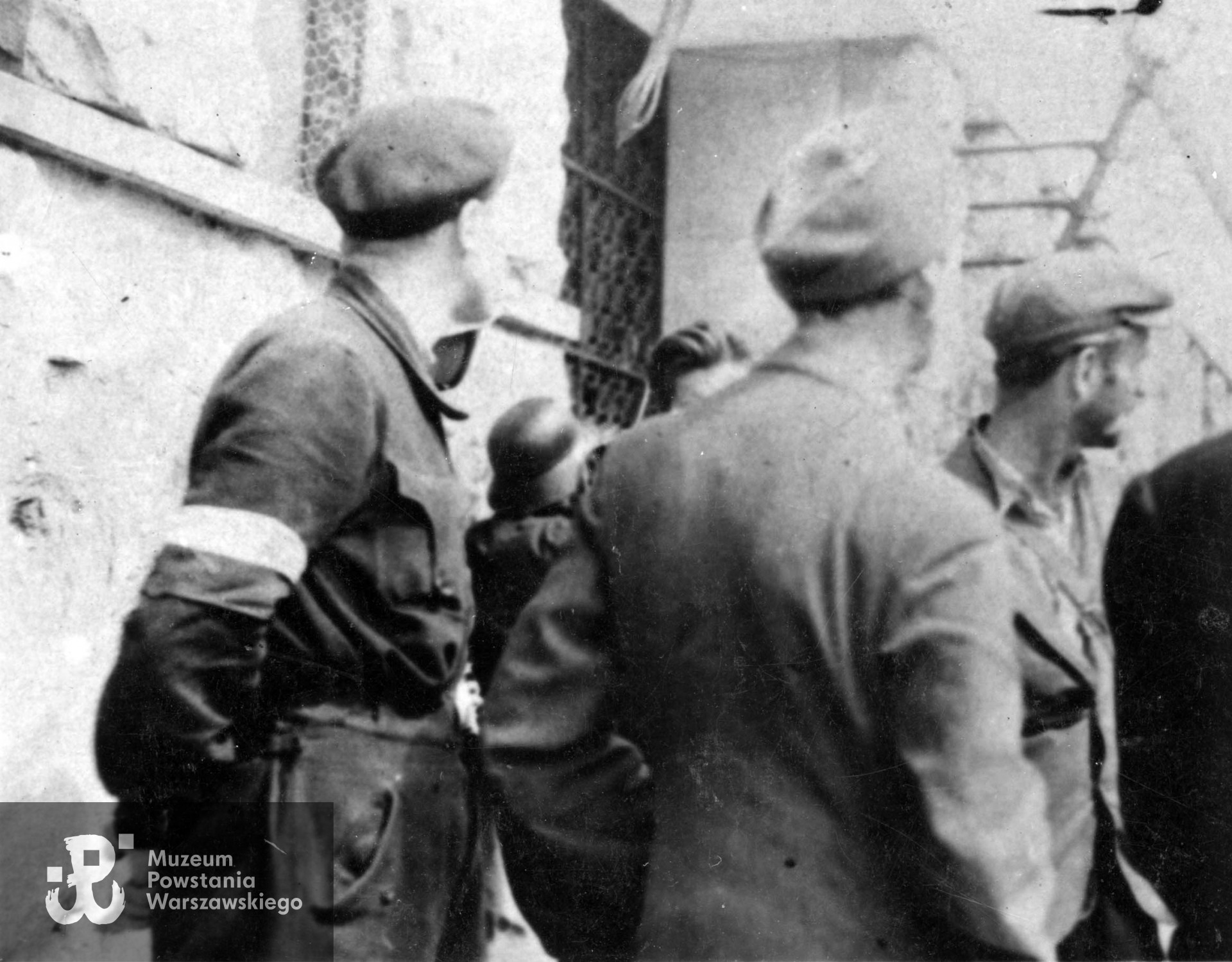 Fotografia z Powstania Warszawskiego.  Żołnierze  "Leśnika" przed gmachem Sądu Grodzkiego na ul. Ogrodwej. Tyłem stoi ppłk Jan Szypkowski "Leśnik", po prawej w cyklistówce pchor. Stefan Kowalski "Jaroń". Fot. ze zbiorów Muzeum Powstania Warszawskiego, sygn. MPW-IK/1318