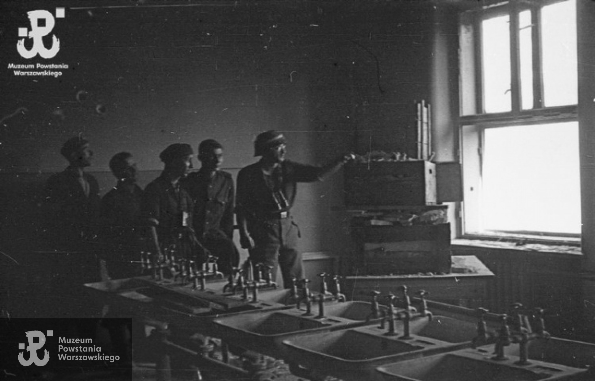 Fotografia z Powstania Warszawskiego. Ppor. Władysław Zajdler "Żarski" dowódca półplutonu 137 kompanii "Tadeusz" batalionu "Ruczaj" z grupą żołnierzy przy stanowisku ogniowym w umywalni budynku Poselstwa Czechosłowackiego przy ul. Koszykowej 18. Autorem zdjęcia jest  Marian Grabski "Wyrwa", ze zbiorów Muzeum Powstania Warszawskiego, sygn. MPW-IN/1461