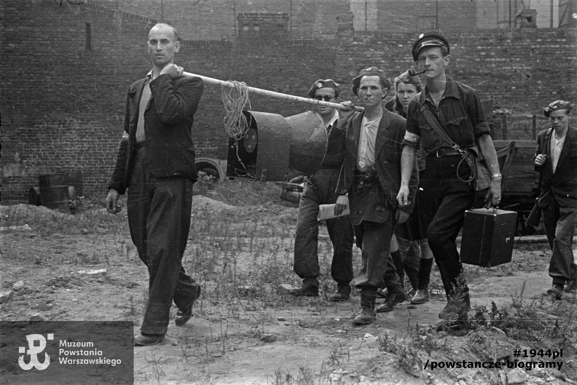 Fotografia z Powstania Warszawskiego. Grupa powstańców na podwórzu kamienicy przy |Drewnianej 7. Z przodu Filip Trzaska ps. „Siedlecki”, z prawej  Janusz Kulesza ps „Super” (w koszuli z podwiniętymi rękawami). Za Kuleszą w furażerce Kazimiera Bakalarska „Krysia". Fot. ze zbiorów Muzeum Powstania Warszawskiego, sygn. MPW-IN/12110. Autorem zdjęcia jest Tadeusz Bukowski ”Bończa„ 