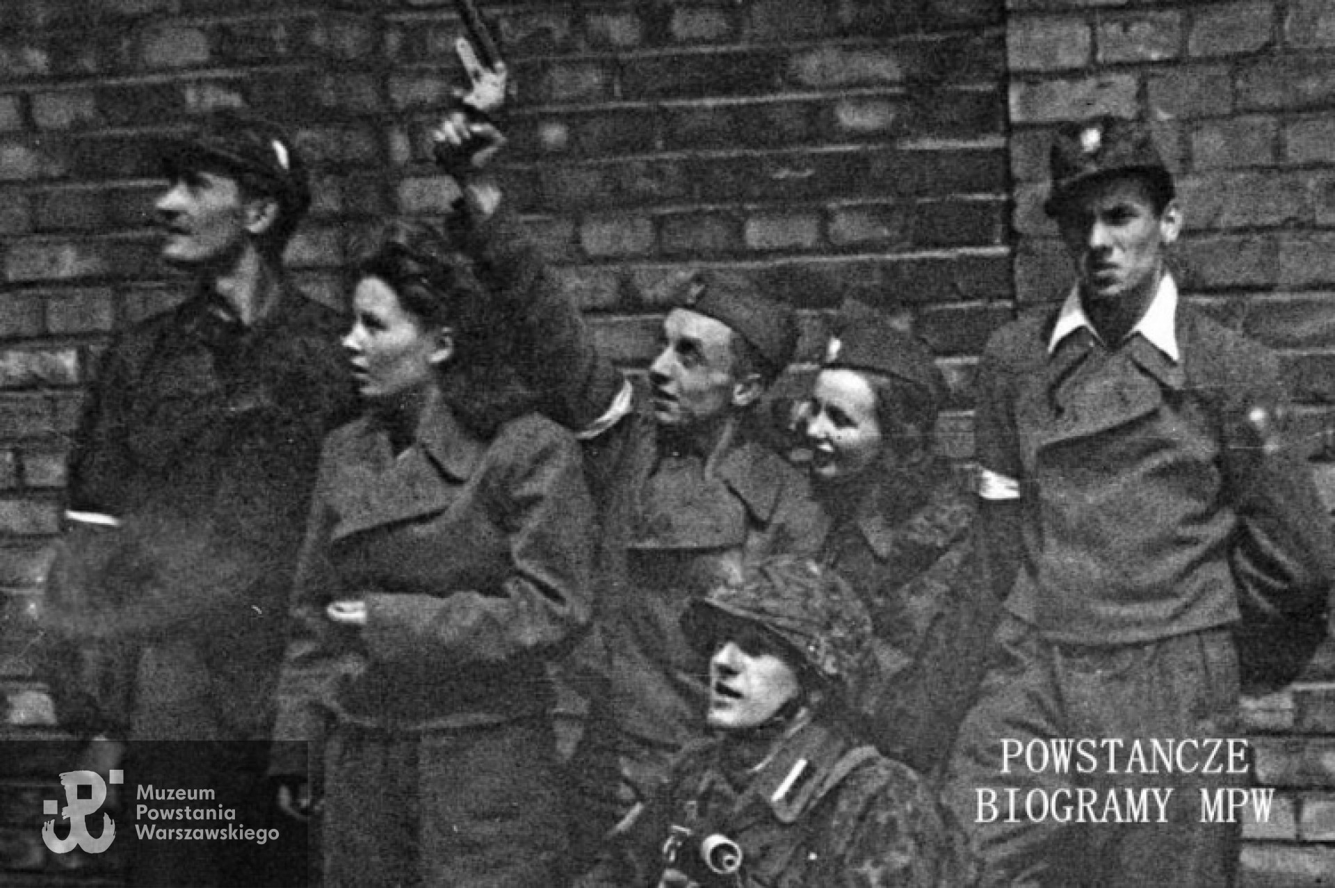 Fotografia z Powstania Warszawskiego - fragment szerszego ujęcia. Grupa powstańców z Batalionu "Miotła" pluton "Torpedy", od lewej: ppor. Marian Ławacz "Marek", łączniczka Krystyna Trzaska "Krysia", plut. pchor. Zenon Jackowski "Adam Horski", Danuta Marciniak - Aniszewska "Danka", kpr. pchor. Zbigniew Wojterkowski "Bogdan", klęczy plut. pchor. Jan Romańczyk "Łata". Fot. ze zbiorów Muzeum Powstania Warszawskiego, sygn. MPW-IN/4280. Autorem zdjęcia jest Jerzy Michalski "Korczak"