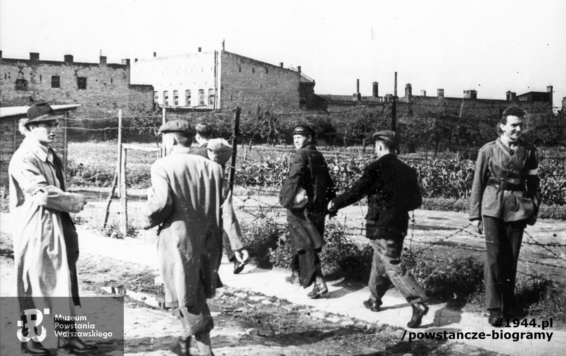  Fotografia z Powstania Warszawskiego. Wola. Godzina "W". Grupa powstańców z Batalionu "Pięść" udająca się na koncentrację w rejonie cmentarza ewangelicko-augsburskiego. Po lewej stoi w jasnym płaszczu ppor. Stanisław Bąk "Burza". Ujęcie w kierunku północnym. W tle widoczne zabudowania przemysłowe stojące wzdłuż ul. Mireckiego. Autorem zdjęcia jest Stefan Bałuk. Ze zbiorów Muzeum Powstania Warszawskiego, sygn. MPW-IH/3410. Prawa autorskie MPW