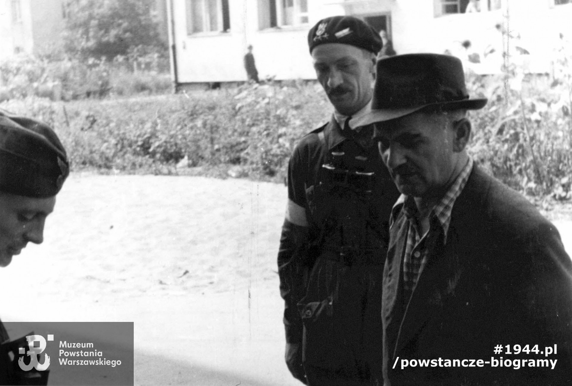 Zdjęcie filmowe z Powstania Warszawskiego autorstwa Romana Banacha ps. "Świerk".   Mokotów, ulica Puławska 132. Dowódca pułku "Baszta" ppłk Stanisław Kamiński "Daniel" (w kapeluszu) dokonuje przeglądu przybyłej z Lasów Chojnowskich kompanii "Krawiec". Za nim w berecie rtm. Lech Głuchowski "Jeżycki" dowódca dywizjonu "Jeleń".  Z lewej por. Stanisław Milczyński "Gryf", dowódca kompanii "Krawiec". W tle budynek Puławska 130A. Ze zbiorów Muzeum Powstania Warszawskiego, sygn.  MPW-IP/3324, ujęcia podobne: MPW-IH/1269 oraz MPW-IK/1678.