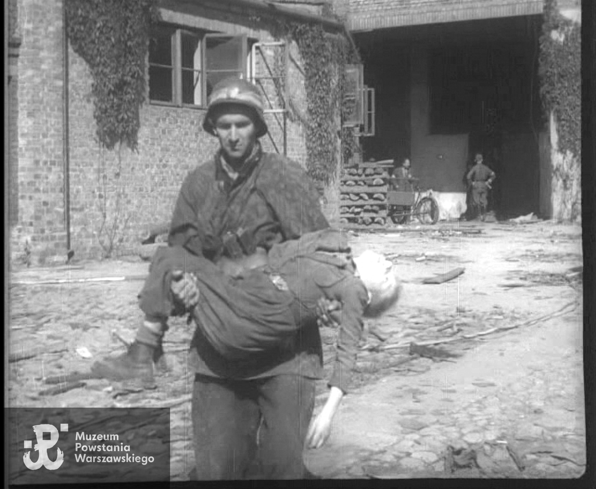 Kadr z Powstańczej Kroniki Filmowej - powstaniec niosący ciało "Orła Białego" wyciągnięte przed chwilą spod niemieckiego ognia. Na zdjęciu - Mieczysław Mirecki "Błyskawica"