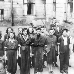 Fotografia z Powstania Warszawskiego. Śródmieście Południowe. Sanitariuszki i łączniczki z 1. plutonu „Kłosa” 3. kompanii „Redy” batalionu „Miłosz” podczas mszy św. odprawianej na podwórzu kamienicy przy ul. Mokotowskiej.  W pierwszym rzędzie stoją od lewej: w hełmie Ryszard Lewandowski „Oporek”, za nim nieco zasłonięty łącznik Ziuk (w jasnej kurtce), łącznik NN, obok niego Wacława Sutowska ps. Aćka,   Hanna Baranowska „Lalka”, Krystyna Kleszczewska „Krysia”, patrolowa „Teresa” (prawdopodobnie  Zofia Tomasik), Janina Kleszczewska „Kopernik„, NN, NN. W drugim rzędzie stoją: za „Aćką” - „Dzidka” (prawdopodobnie Helena Schabińska), obok niej Daniela Białowąs „Niutka” (za H. Baranowską „ Lalką