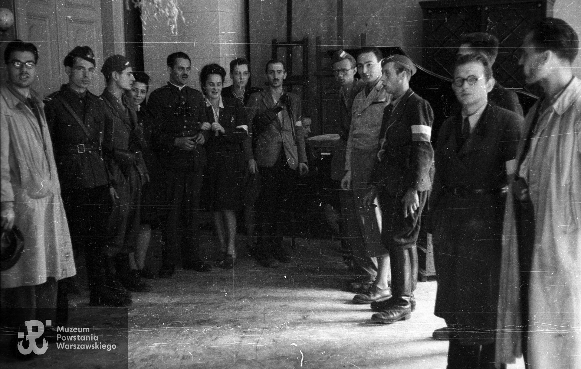 Fotografia z Powstania Warszawskiego. Żołnierze z kompanii "Grażyna" Batalionu "Harnaś" w kwaterze przy ulicy Mazowieckiej 4. Od lewej: NN, kpr. pchor. Ryszard Benedykciński "Niesiołowski", ppor. Konrad Niklewicz "Konrad", sanitariuszka Alicja Moszkowska "Lilka", por. Marian Krawczyk "Harnaś", NN, NN, ppor. Zbigniew Siciński "Kazimierz", kpr. Stefan Medwadowski "Poraj", NN, plut. pchor. Bolesław Koucki "Kocio", NN, NN, NN. Fot. ze zbiorów Muzeum Powstania Warszawskiego, sygn. MPW-IN/3256.