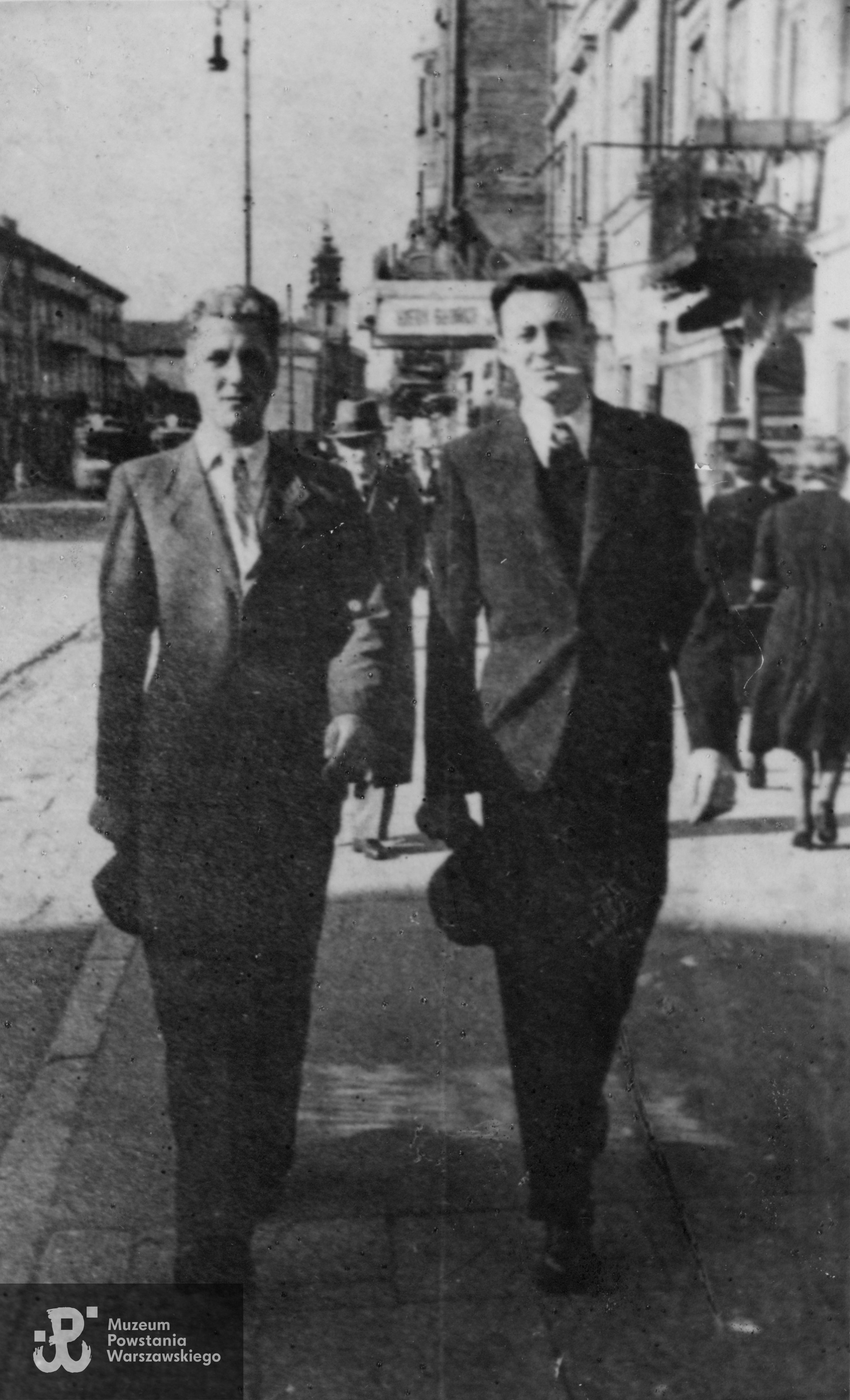 Jerzy Bronowski "Błysk" (z prawej) i  Tadeusz Kujawski "Dzik" (z  lewej). Fotografia wykonana w Warszawie w okresie okupacji niemieckiej. W tle widoczny kościół św. Krzyża przy Krakowskim Przedmieściu. Fot. ze zbiorów Muzeum Powstania Warszawskiego, sygn. P/5426