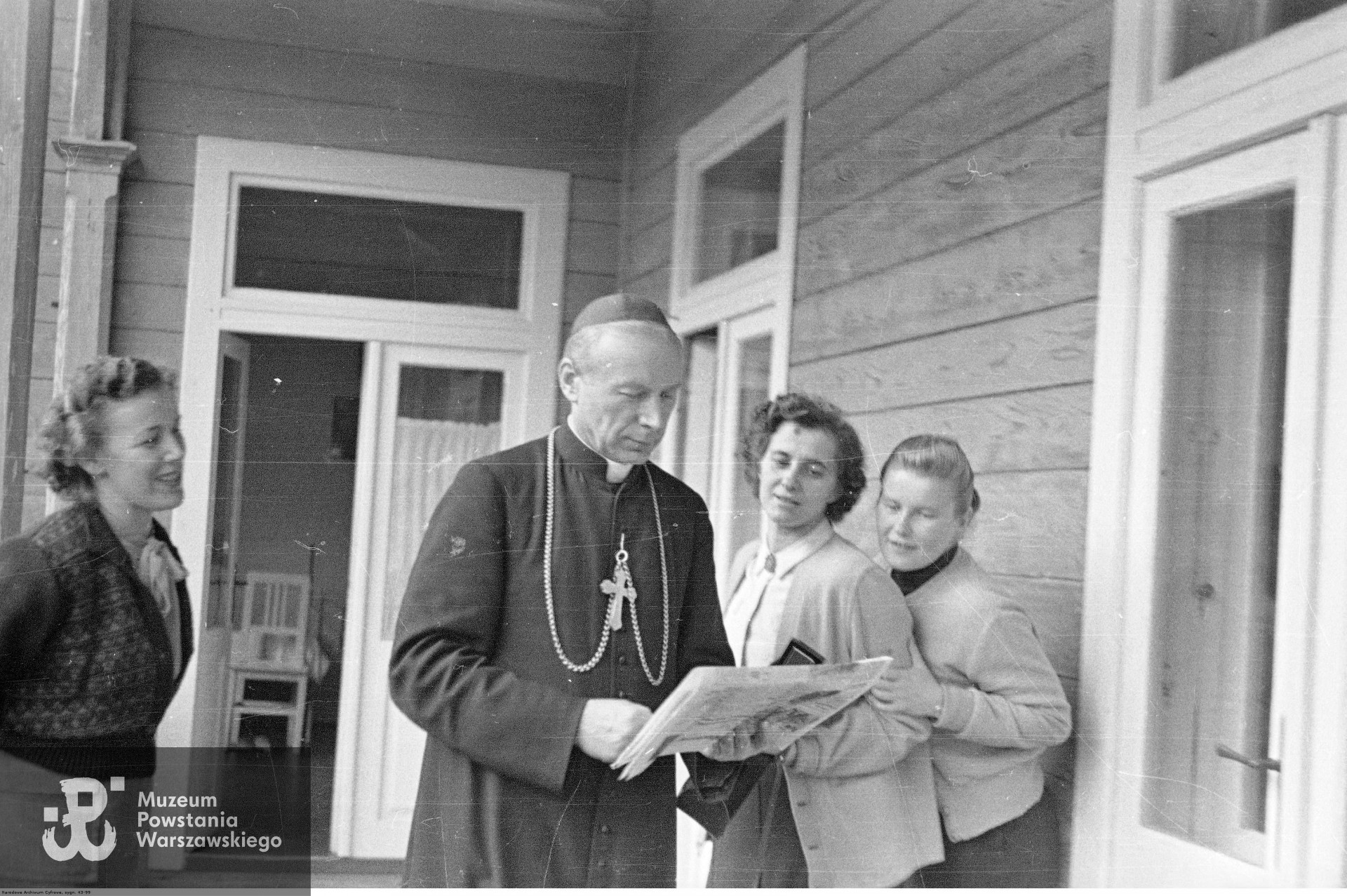 1956 rok. Ks. kard. Stefan Wyszyński   w towarzystwie siostrzenicy Danuty Marii Sułek (1. z lewej) oraz członkiń Instytutu Świeckiego Pomocnic Maryi Jasnogórskiej Matki Kościoła  - Marii Wantowskiej (1. z prawej) i Marii Okońskiej (2. z prawej) na werandzie domu SS. Nazaretanek. Fotografia wykonana  podczas internowania Prymasa w Komańczy. Fot. ze zbiorów Narodowego Archiwum Cyfrowego, zespół:Archiwum Fotograficzne Stanisława Porębskiego.  <i>audiovis.nac.gov.pl</i>
