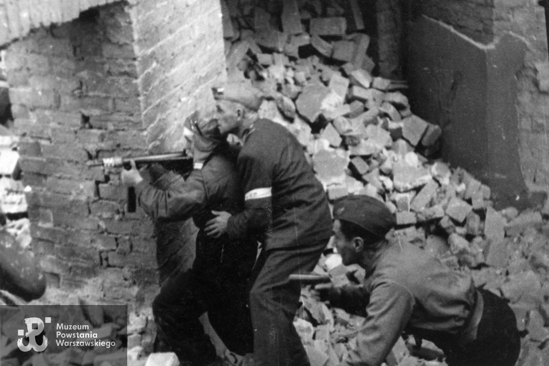 Powstanie Warszawskie, wrzesień 1944. Śródmieście Północ. Rejon ul. Górskiego. Zdjęcie filmowe: Wanda Traczyk (w pilotce) z oddziału osłonowego WZW na stanowisku. Widoczni także płk. Radwan i  ppłk. "Wola" (z tyłu). Fot. Stefan Bagiński, zbiory Muzeum Powstania Warszawskiego, sygn. MPW-IP/1934 (P/3407).