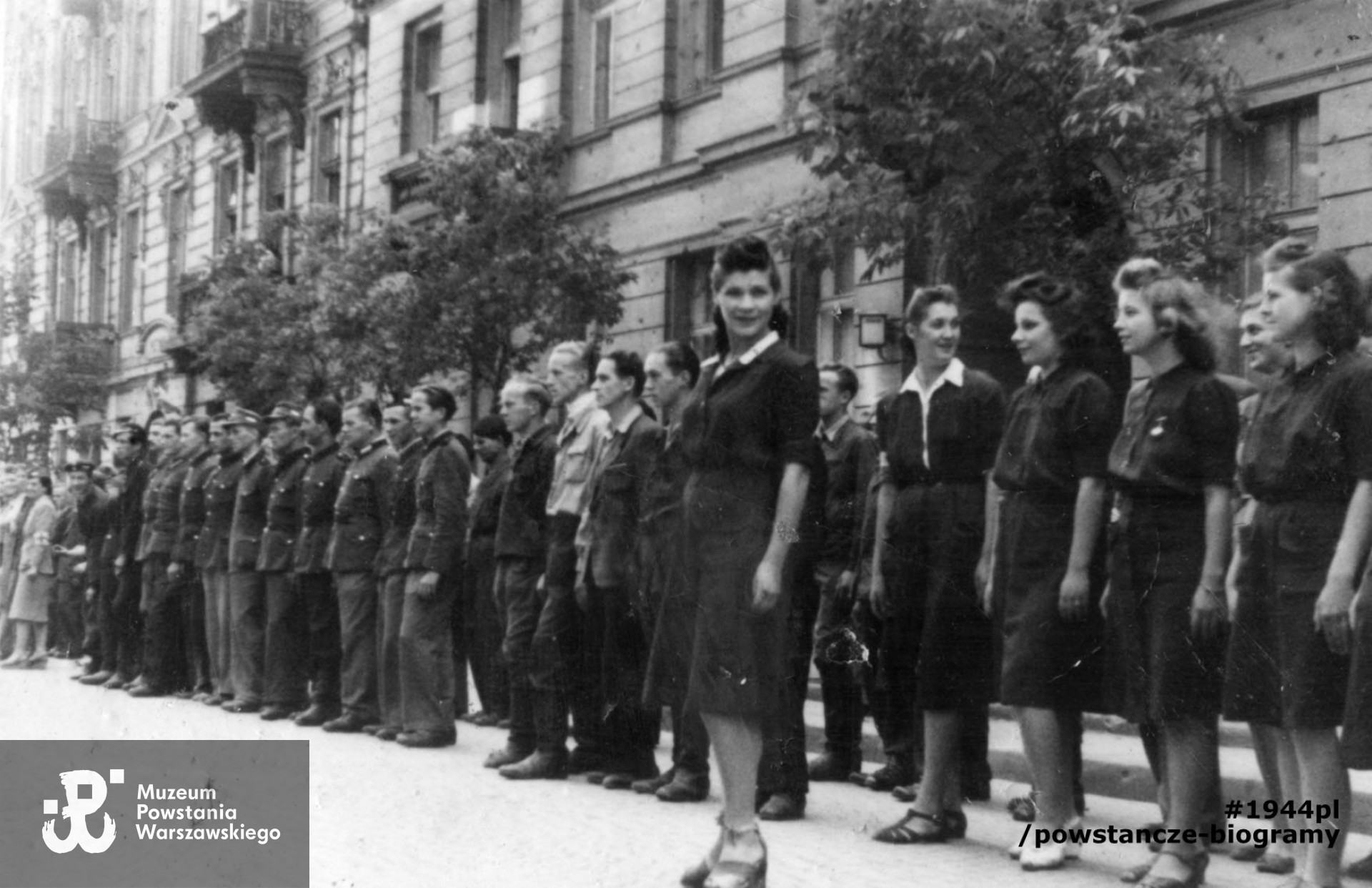 Fotografia z Powstania Warszawskiego. Śródmieście Północne. Zbiórka oddziałów powstańczych na ul. Boduena. W tle od prawej Dom Dochodowy Warszawskiego Towarzystwa przy ul. Boduena 3 i kamienica przy ul. Boduena 1. Autorem zdjęcia jest Witold Romański "Kuba", PSW. Fot. ze zbiorów Muzeum Powstania Warszawskiego, sygn. MPW-IP/6949. Według informacji przekazanych przez rodzinę p. Janiny kobieta stojąca przed oddziałem to najprawdopodobniej Janina Wierusz-Kowalska ps. Dzidzia.  Według tej samej identyfikacji rodzinnej na zdjęciu widoczna jest także bliska koleżanka Janiny - Izabela Czajkowska „Anna”  - druga z prawej stojąca w rzędzie. W zasobach ikonograficznych MPW obie te osoby nie są opisane i ich tożsamość nie jest znana.