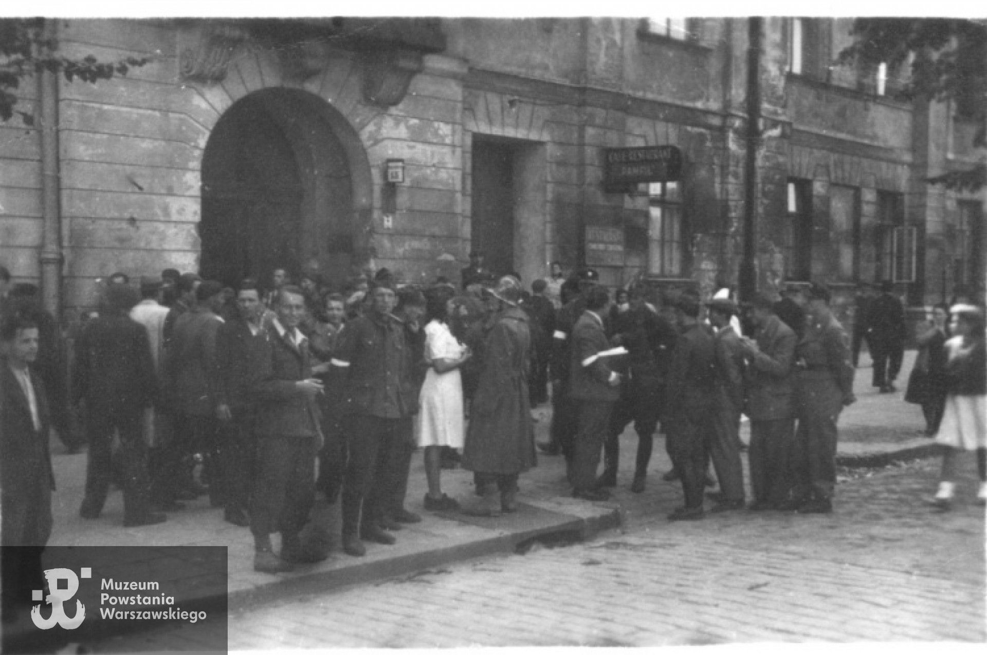 Powstanie Warszawskie, 6.08.1944, przygotowania do jedynej powstańczej defilady. Grupa powstańców i ludności cywilnej stoi przed budynkiem Długa 13