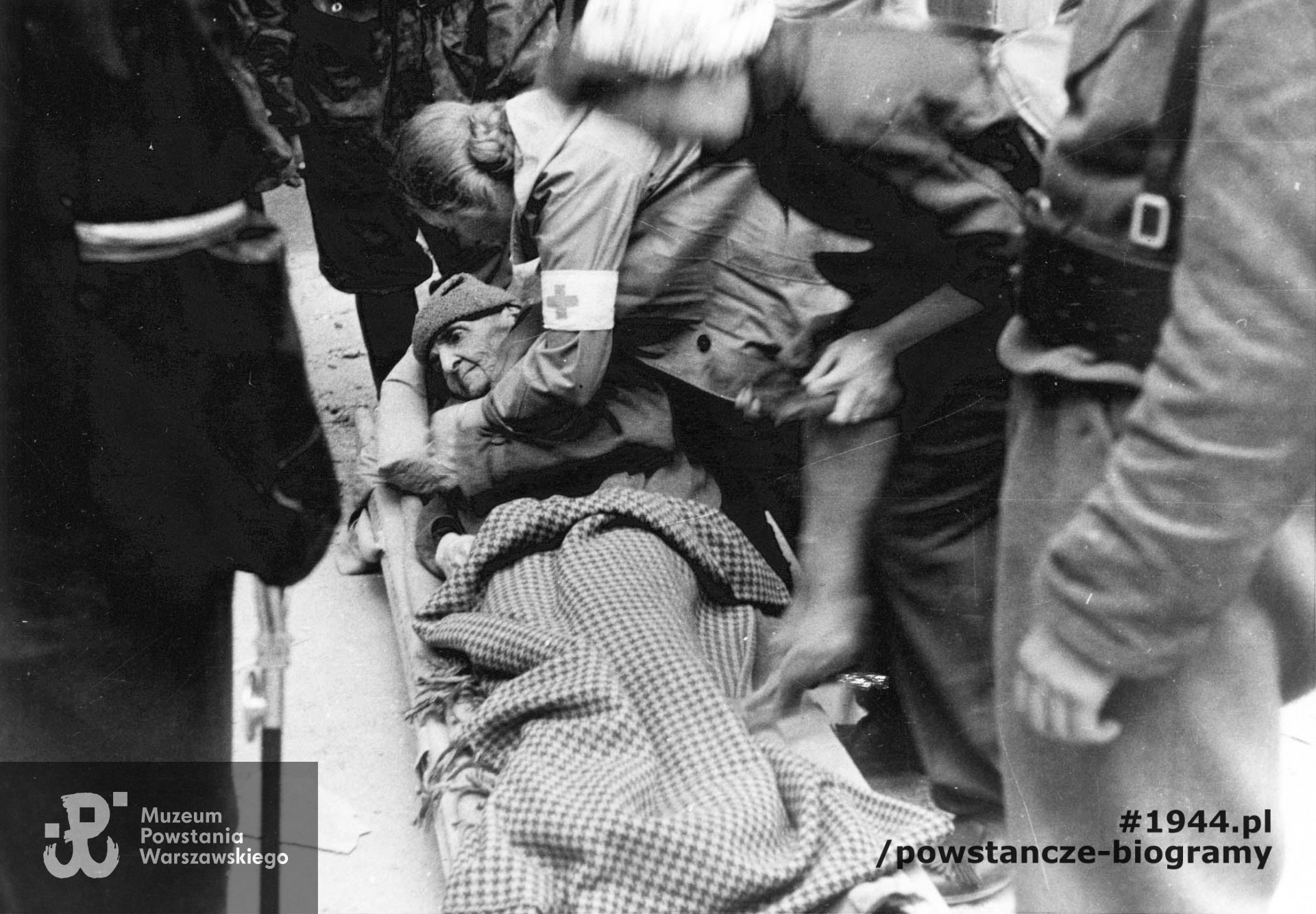 Fotografia wykonana podczas Powstania Warszawskiego. Śródmieście Północne. Patrol sanitarny z III Zgrupowania "Konrad" przed sklepem "Wedla", przy ul. Szpitalnej 8, podczas ewakuacji pisarki Marii Rodziewiczówny. Autorem zdjęcia jest Antoni Bohdziewicz. Fot. ze zbiorów Muzeum Powstania Warszawskiego, sygn. MPW-IP/3202