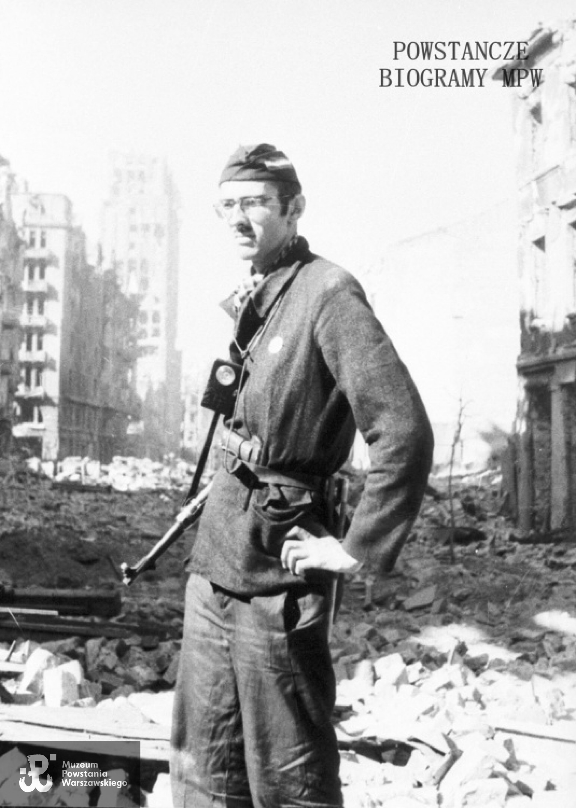 Powstanie Warszawskie. Śródmieście Północ. Ul. Szpitalna. Strz. Janusz Paszyński "Machnicki" z III zgrupowanie "Konrad"  z latarką i pistoletem. Zdjęcie pozowane. W tle Prudential - siedziba angielskiego Towarzystwa Ubezpieczeń „Prudential”.przy placu Napoleona 9 (obecnie plac Powstańców Warszawy). Fot. ze zbiorów Muzeum Powstania Warszawskiego, sygn. MPW-IH/4354
