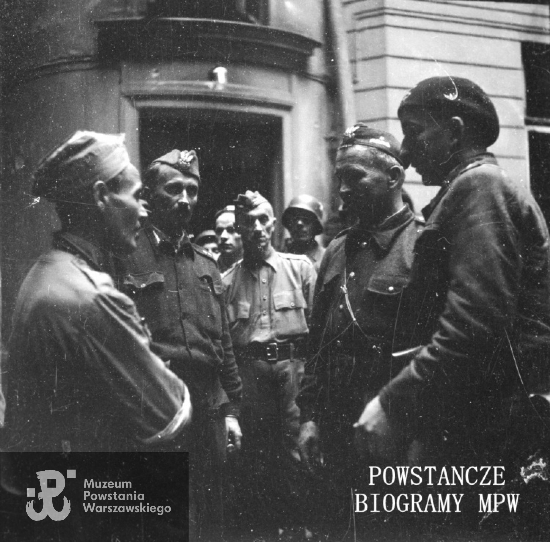 Fotografia z Powstania Warszawskiego autorstwa Jerzego Einhorna ps. "Sław". Śródmieście Południowe, ul. Poznańska 12. Generał Leopold Okulicki "Niedźwiadek" (drugi z prawej) podczas inspekcji na placówce Batalionu "Zaremba-Piorun", dowodzonego przez kpt. Franciszka Malika "Pioruna".  Fot. ze zbiorów Muzeum Powstania Warszawskiego, sygn. MPW-IN/9033