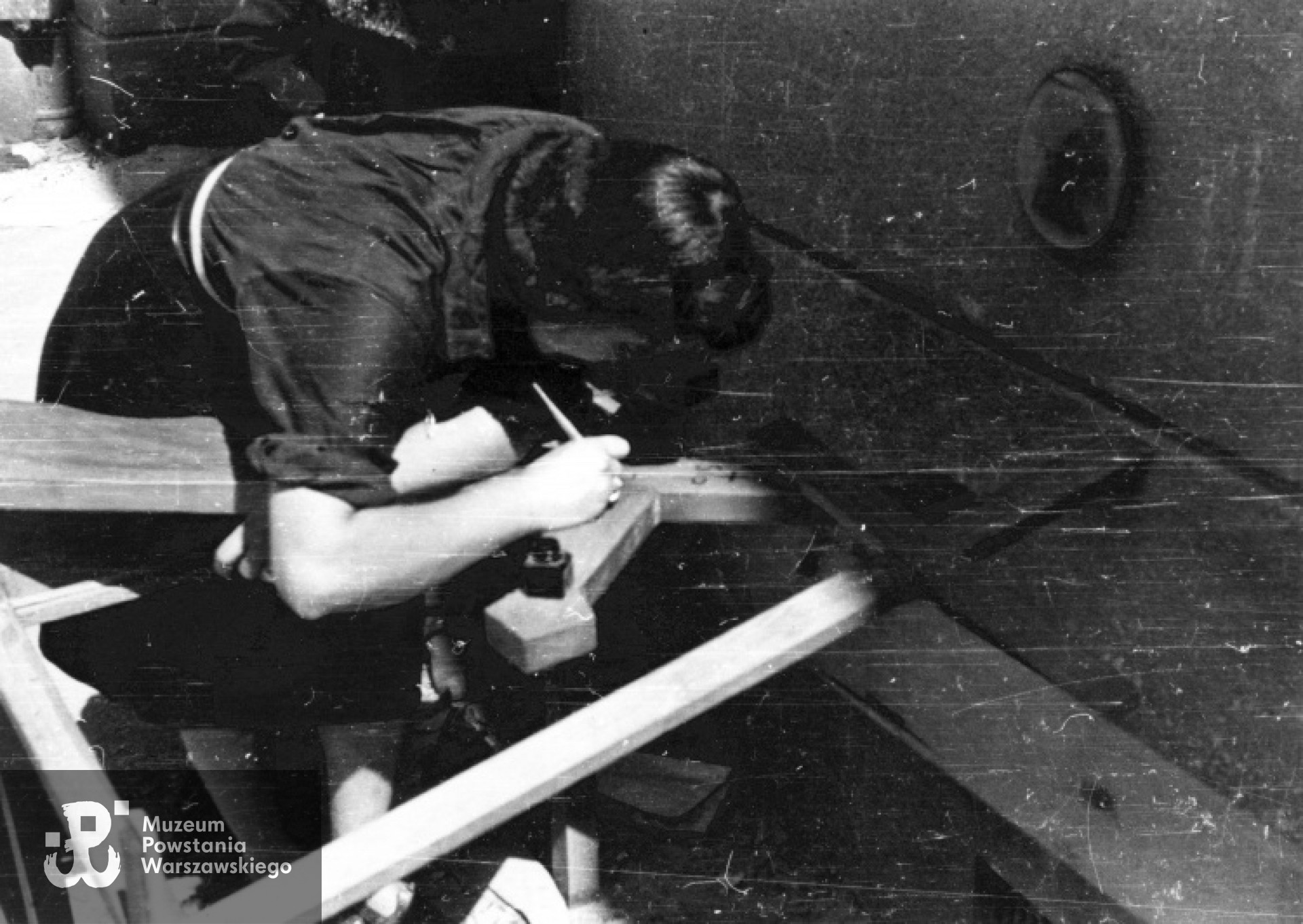 Ulica Mazowiecka. Łączniczka Jadwiga Maydell ps. Jadwiga z plutonu 1147 pisze na krzyżu imię i nazwisko  dowódcy por. Kazimierza Pogorzelskiego "Rygla", który zginął 2 sierpnia na Placu Małachowskiego. Fot. Eugeniusz Lokajski "Brok". Ze zbiorów Fototeki MPW, sygn. MPW-IN/241, prawa autorskie MPW