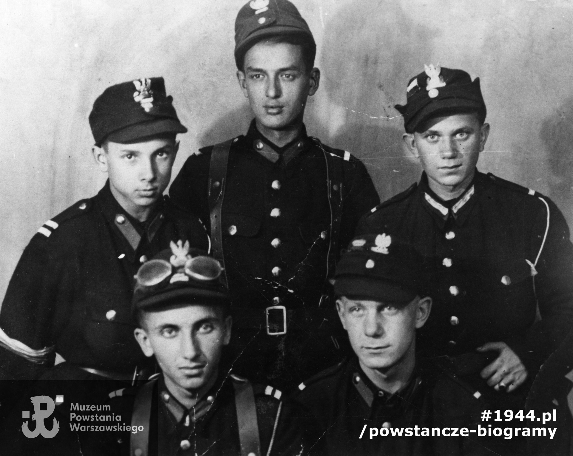 Fotografia z okresu powstania warszawskiego wykonana w zakładzie fotograficznym Edwarda Korka przy ulicy Chmielnej 16. Pięciu powstańców z plutonu 327 obwodu "Waligóra", następnie zgrupowania kpt. "Hala". Widoczni na zdjęciu - kpr. Zdzisław Pastwa "Bohun", kpr. Zenon Kryst "Adler", NN, Eugeniusz Wojciechowski "Siwy", st. strz. Jan Szlęzak "Sokół". Fot. ze zbiorów Muzeum Powstania Warszawskiego, sygn. MPW-IK/3108